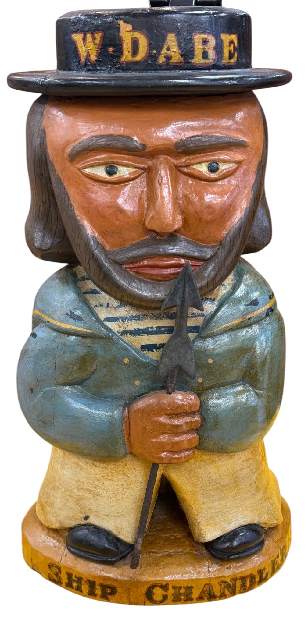 Large Maritime Folk Art Sailor Wooden Carving: A man in a sailors uniform and hat with W Dabe written on the hat, and Ship Chandler on the base. Wood carving measures 25.5 inches x 13.5 inches x 10 inches. Overall good condition, please see
