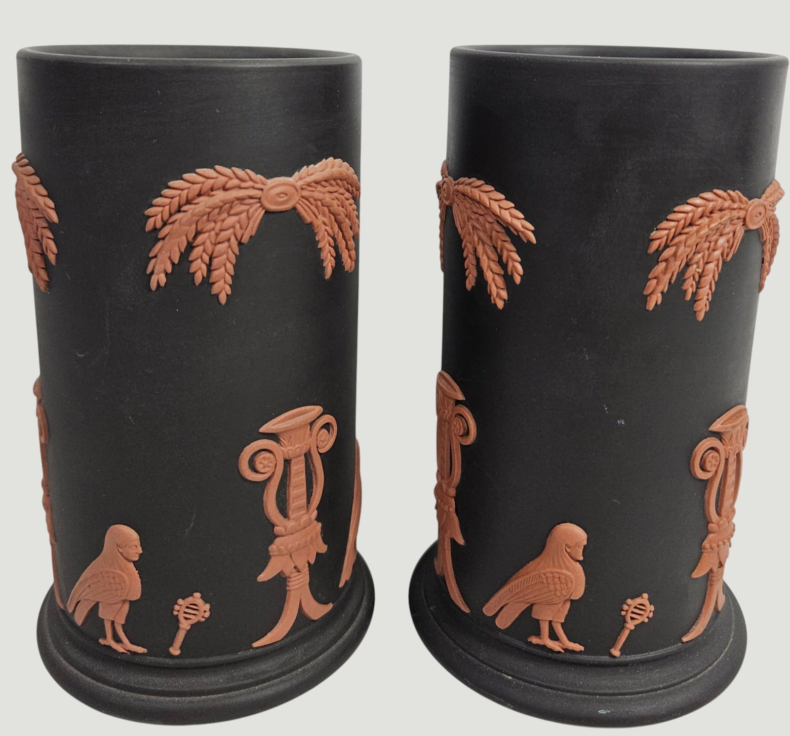 Pair Wedgwood Terracotta on Black Jasperware Egyptian Spill Vases: Matte black ground with terracotta reliefs displaying Egyptian motifs. Wedgwood impressed backstamp. Measure 4.75 inches high, 2.75 inch diameter. Overall good condition, no chips or cracks.
