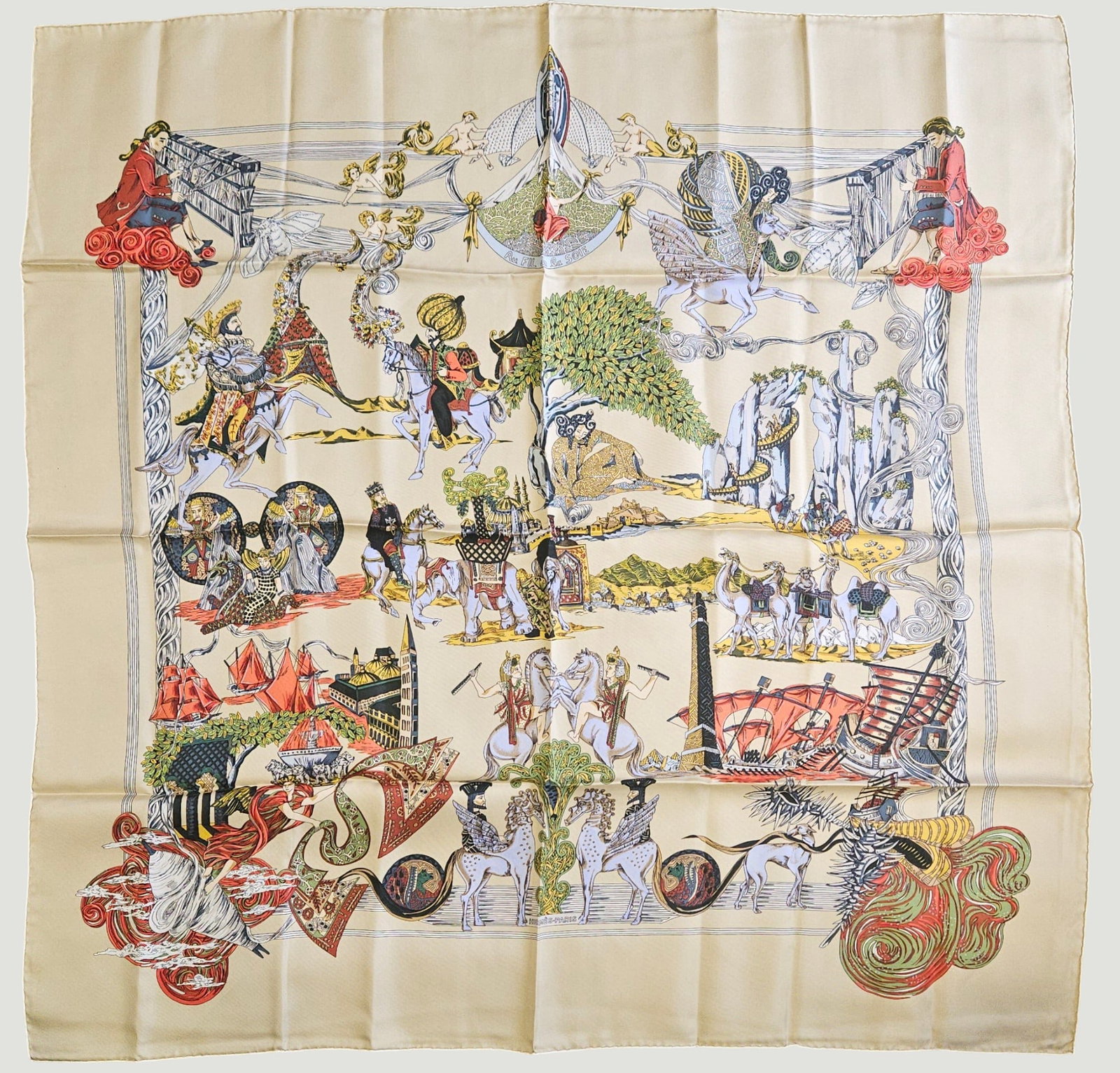 Hermes Au FIl De La Soie Silk Scarf: Original silk screen design c1995 by Annie Faivre features depictions of scenes on the ancient silk road. Weavers, riders, camels, elephants, ships, kings and various mythological creatures in