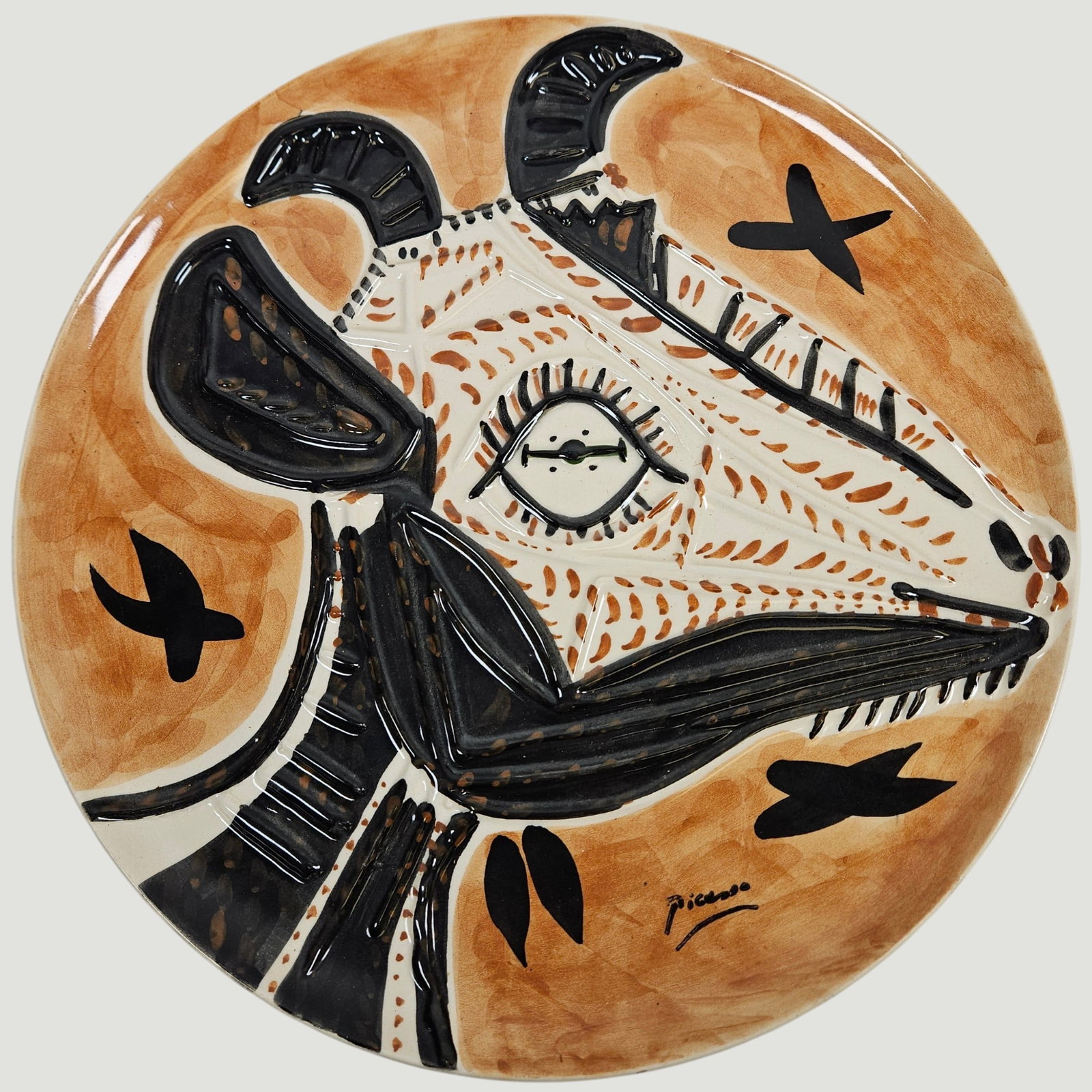 After Pablo Picasso Tête de Chèvre en Profil Plate: Spain / France, 1993, 138/200. White earthenware clay decorated in engobes and brushed glazed, patinated ground. 14.25 inch diameter.