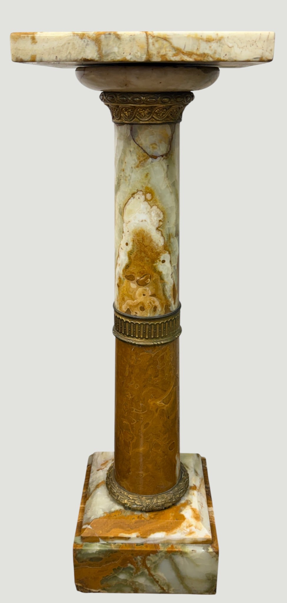 19th Century French Louis XVI Style Onyx & Bronze Pedestal: Crafted from multi-toned natural onyx featuring distinct bands of cream, green and amber. Mounted with cast bronze including a gadrooned capital collar and a central fluted band. Designed with a