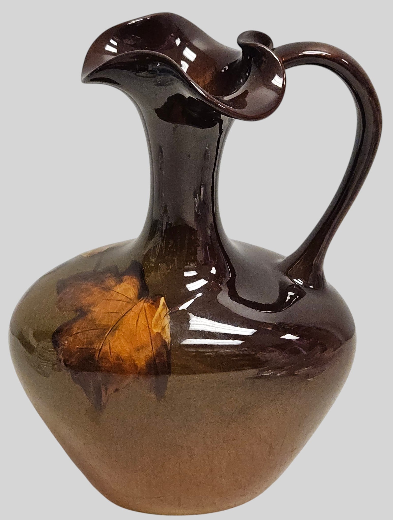 c1889 Rookwood Art Pottery Ewer / Pitcher by Jeanette Swing (1889-1904): American Art Nouveau pottery ewer / pitcher featuring a bulbous base, and elongated hourglass neck, and a gracefully arched applied handle. Hand painted with an underglaze botanical leaf motif against
