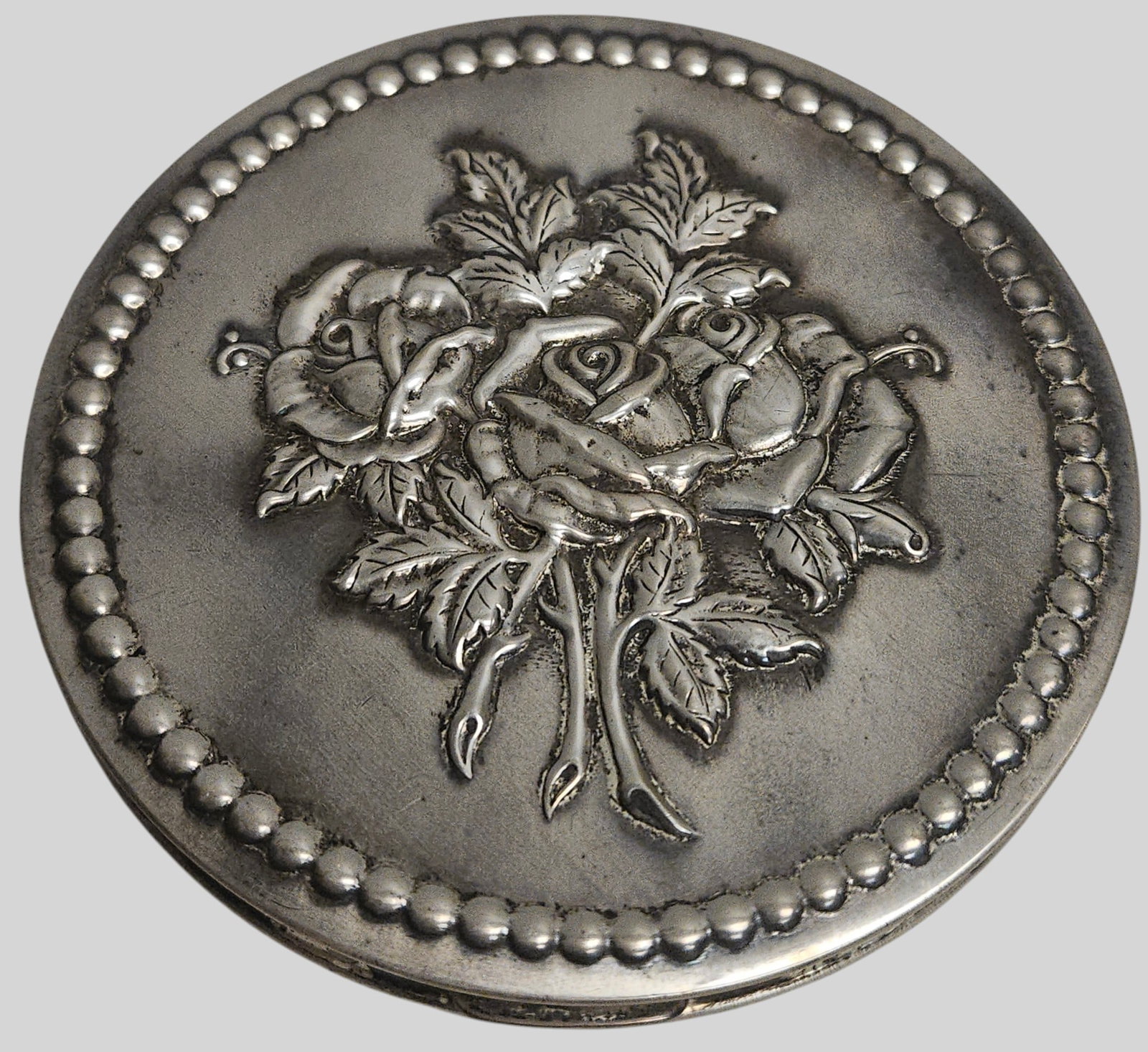 Art Deco Rex Fifth Avenue Sterling Silver Flapjack Powder Compact: Lid features a central rose bouquet design executed in repousse. Back features a classic art deco geometric design consisting of alternating horizontal bands of smooth polished silver and highly detai