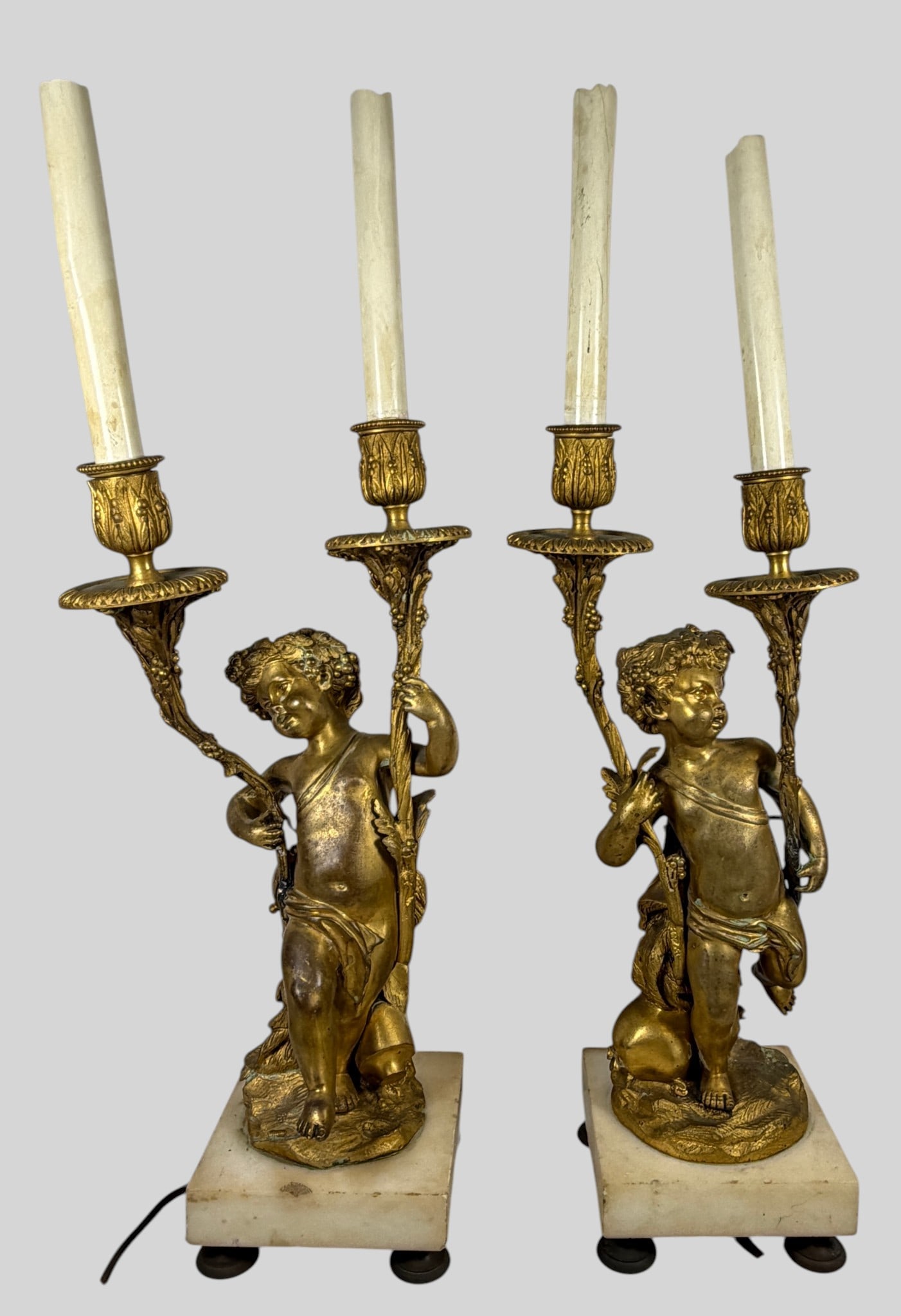 Pair French Louis XVI Style Gilt Bronze Figural Table Lamps after Clodion: Cast after a classic model by Claude Michel Clodion, this fine pair of late 19th-century French Louis XVI style gilt and patinated bronze two-light candelabra has been later adapted as electric table