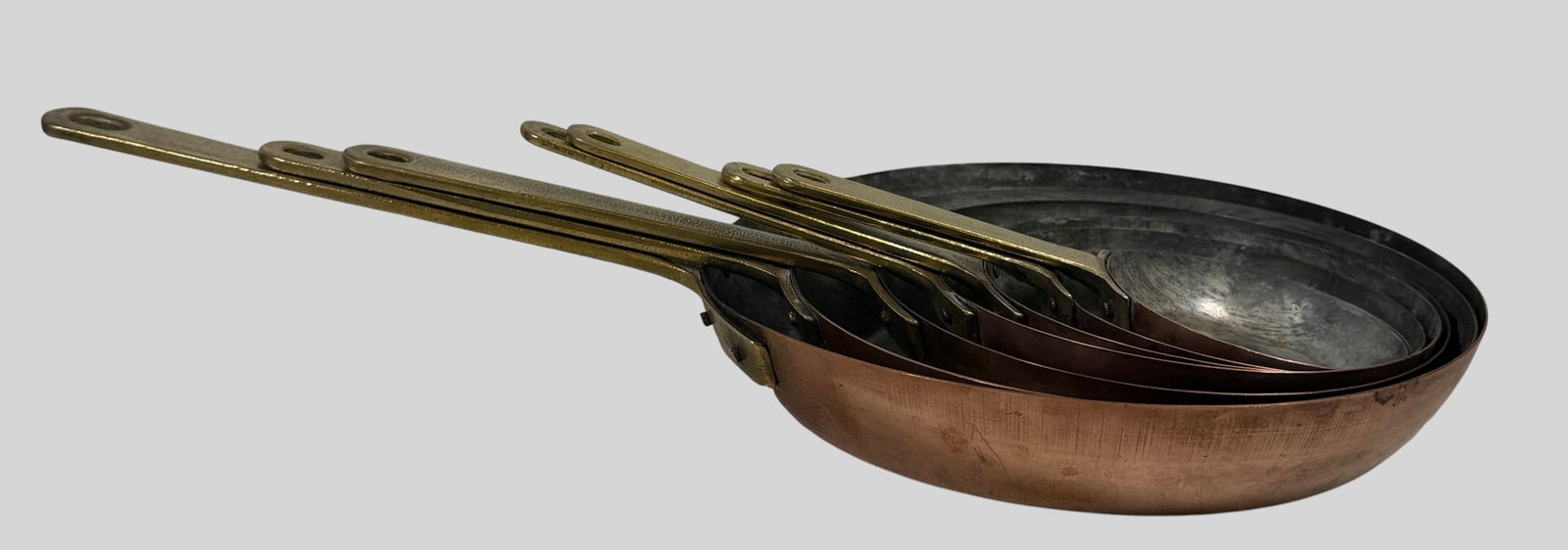 Set of (7) Vintage Nesting Copper Frying Pans with Brass Handles: This exceptional graduated seven-piece nesting set of vintage copper frying pans features heavy-gauge solid copper bodies with a rolled rim, each securely fastened to a robust, textured cast brass han