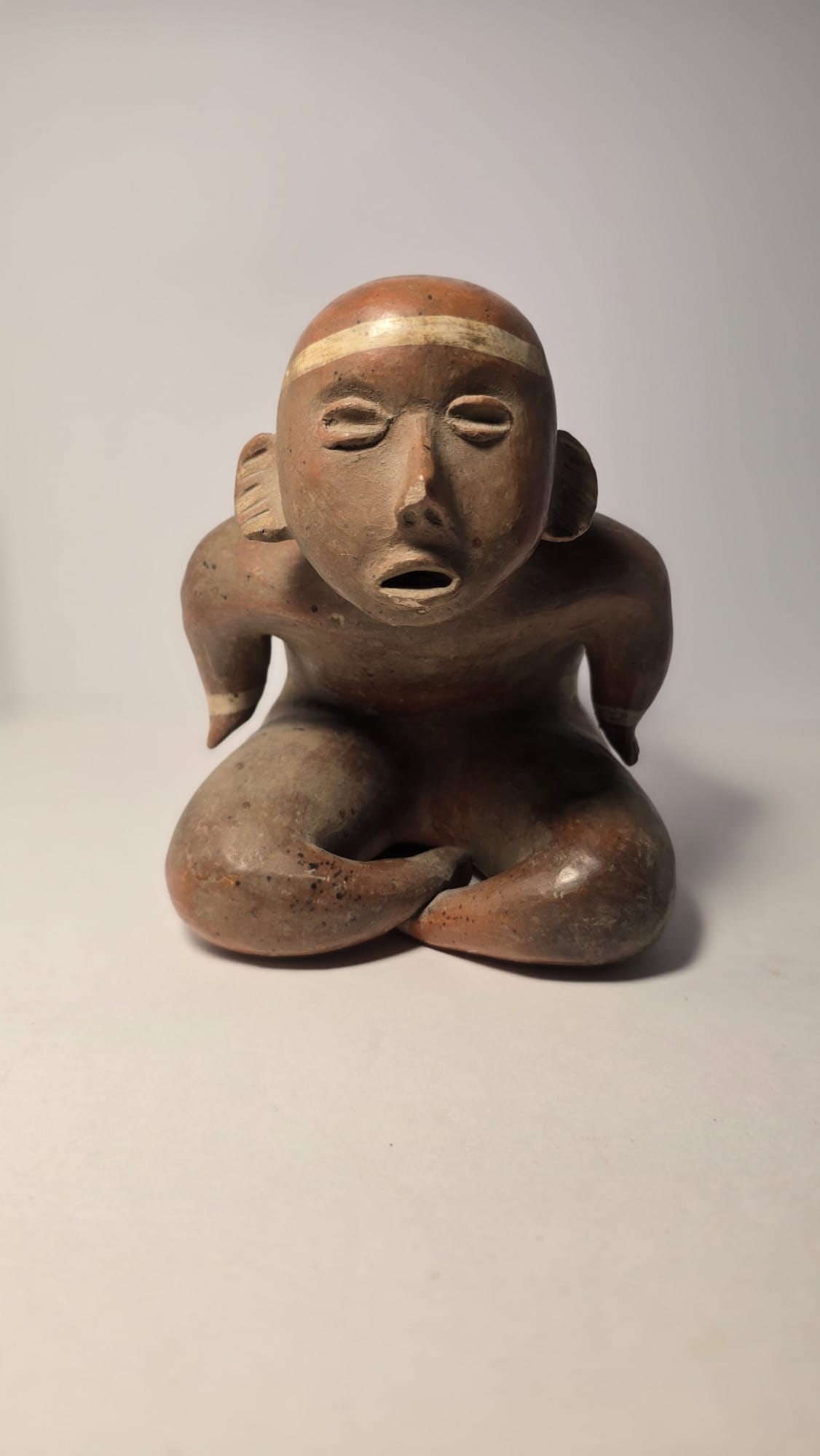 PRE-COLUMBIAN COLIMA HUNCHBACK SEATED FIGURE: PRE-COLUMBIAN COLIMA HUNCHBACK SEATED FIGUREExpressive Colima terracotta seated hunchback figure, dating approximately 100 BC – 250 AD (Protoclassic to Early Classic period, West Mexico). Hunchback