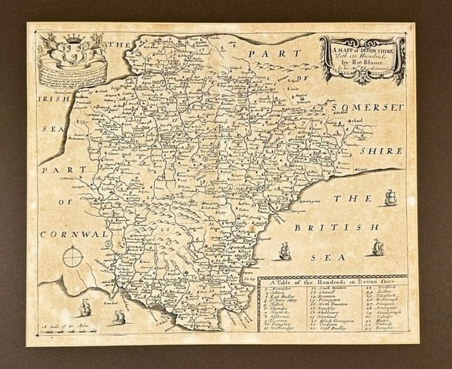 Richard Blome – Map of Devonshire – Copperplate Engraving – Late 17th Century: This richly ornamented map titled A Mapp of Devon Shire with its Hundreds was created by Richard Blome and issued by royal command in the late 17th century. Depicting the English county of Devon, the 