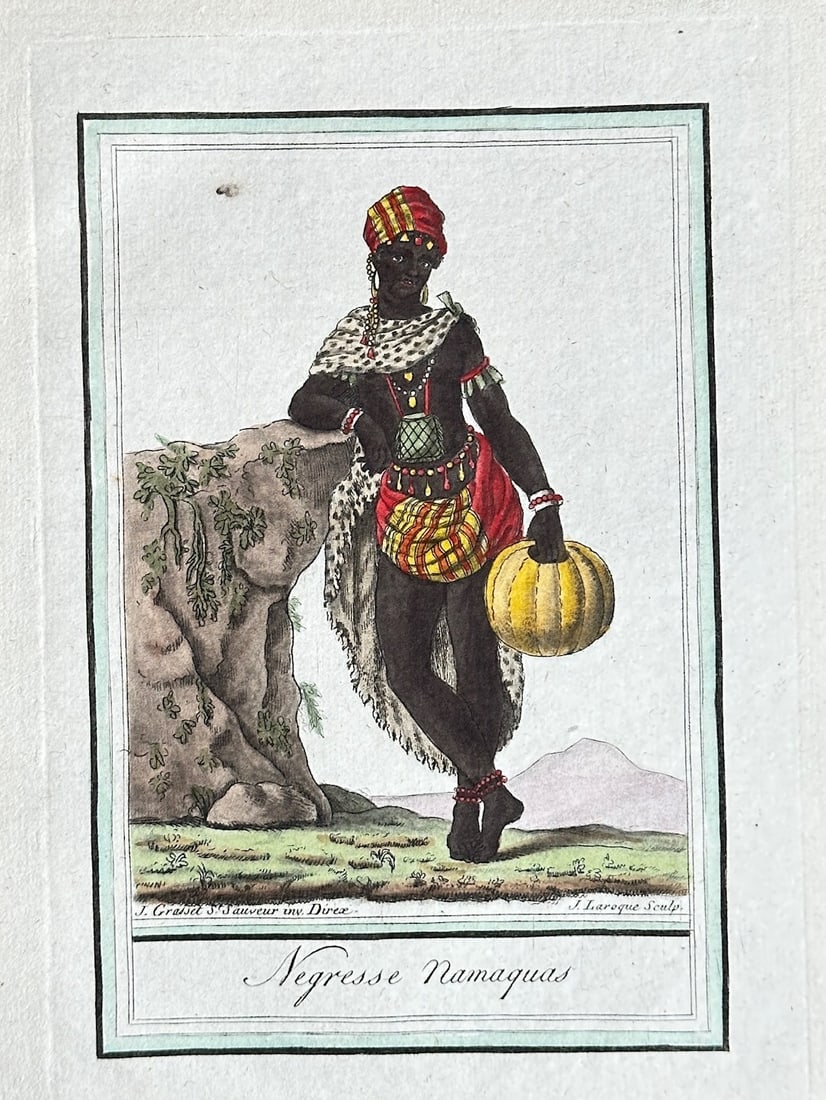Jean-Baptiste-Louis-Claude Grasset de Saint-Sauveur – Namaqua Woman: This hand-coloured engraving from the late 18th-century publication Les Costumes et Usages de tous les peuples du monde depicts a Namaqua woman in traditional dress, leaning against a rock while holdi