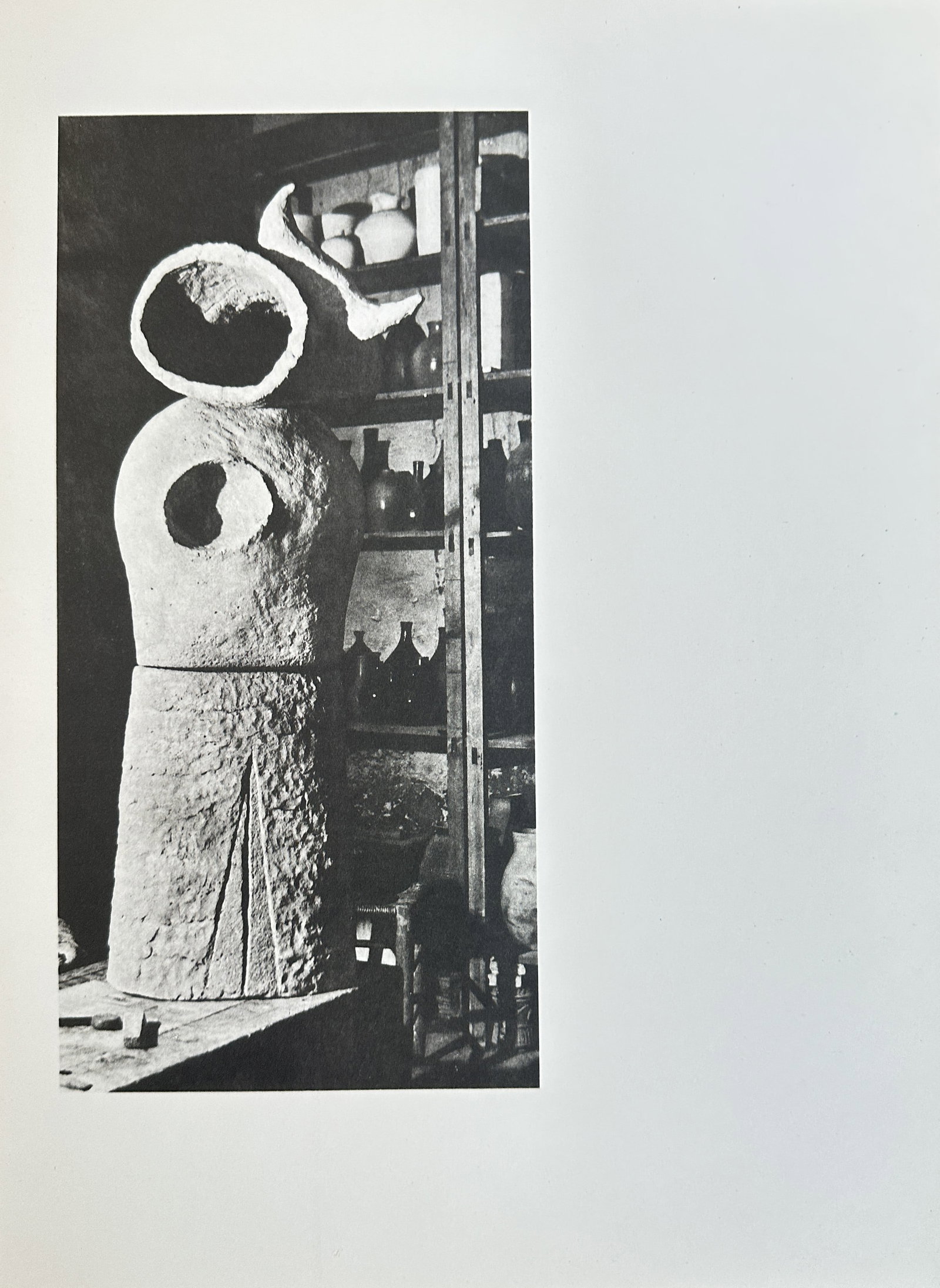 Joan Miró (1893–1983), after – Abstract Ceramic or Plaster Figure in Studio – Offset print: This black and white offset print is a photograph of a sculpture, a preliminary plaster or ceramic figure by the artist, shown in an interior studio setting in front of shelves filled with various cer