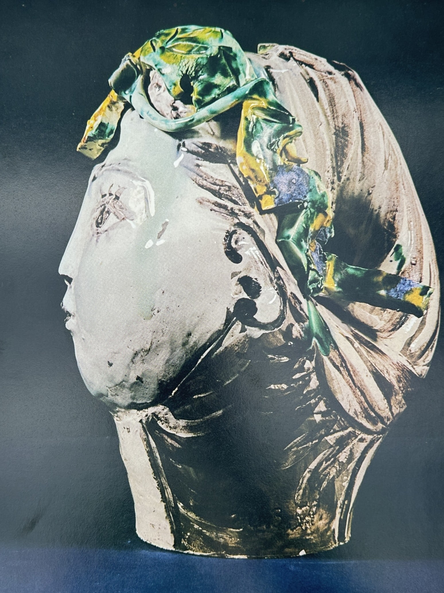 Pablo Picasso (1881–1973), after – Head of a Woman with Scarf – Offset print (20th Century): This illustration depicts a sculptural head of a woman in profile, wearing a vibrant green and yellow patterned scarf or headband. The work showcases the artist's experimentation with ceramic-like tex