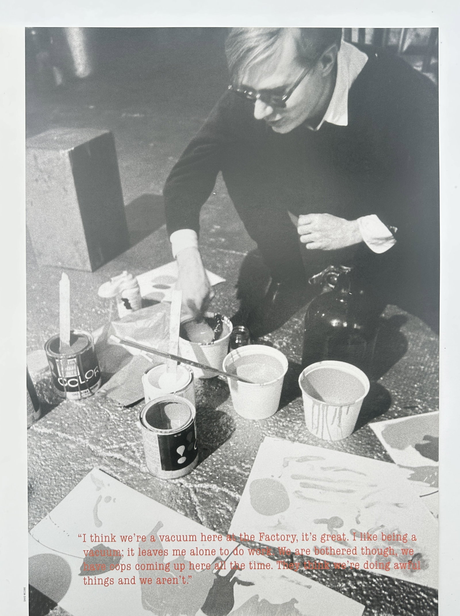 Andy Warhol – Photographic Study of Andy Warhol at The Factory – Screenprint on paper: "I Think We're a Vacuum Here at The Factory" This pop art work features a photographic composition showcasing the artist Andy Warhol crouched on the floor of his studio surrounded by various paint can