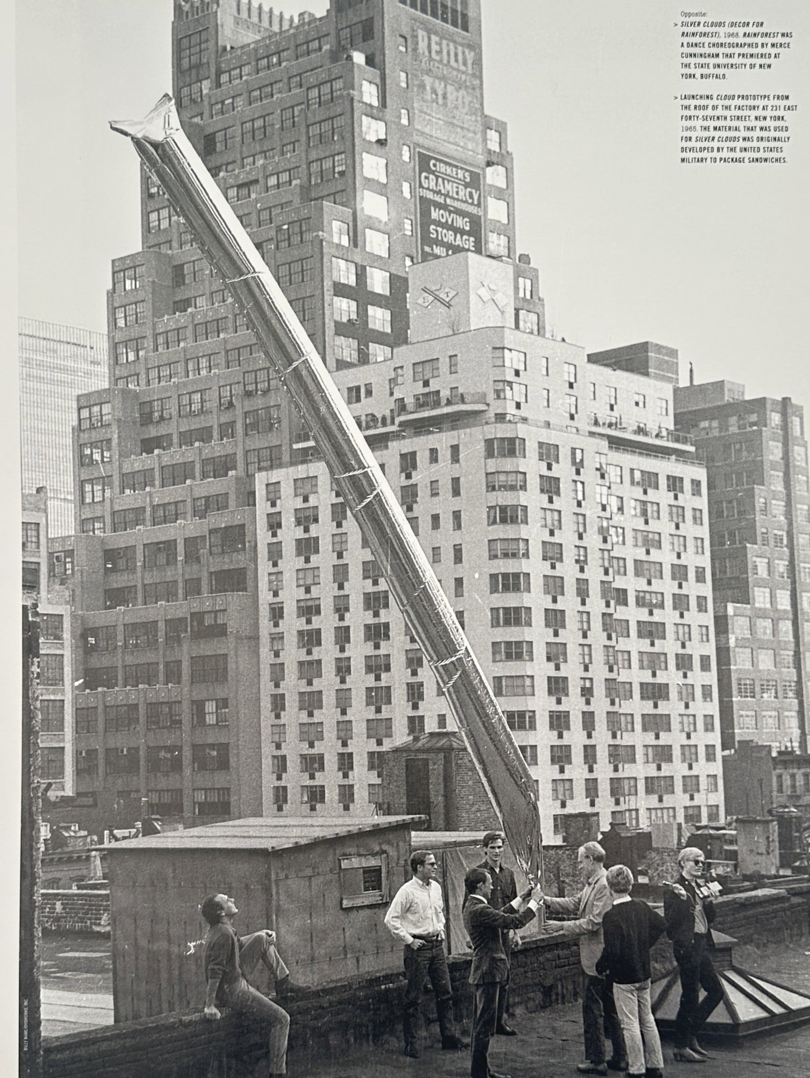Andy Warhol, after - Launching Cloud Prototype - Offset lithographic reproduction (2006): "Launching Cloud Prototype" This work depicts a group of individuals assembled on an urban rooftop handling a large metallic balloon sculpture against a backdrop of city skyscrapers. The image capture