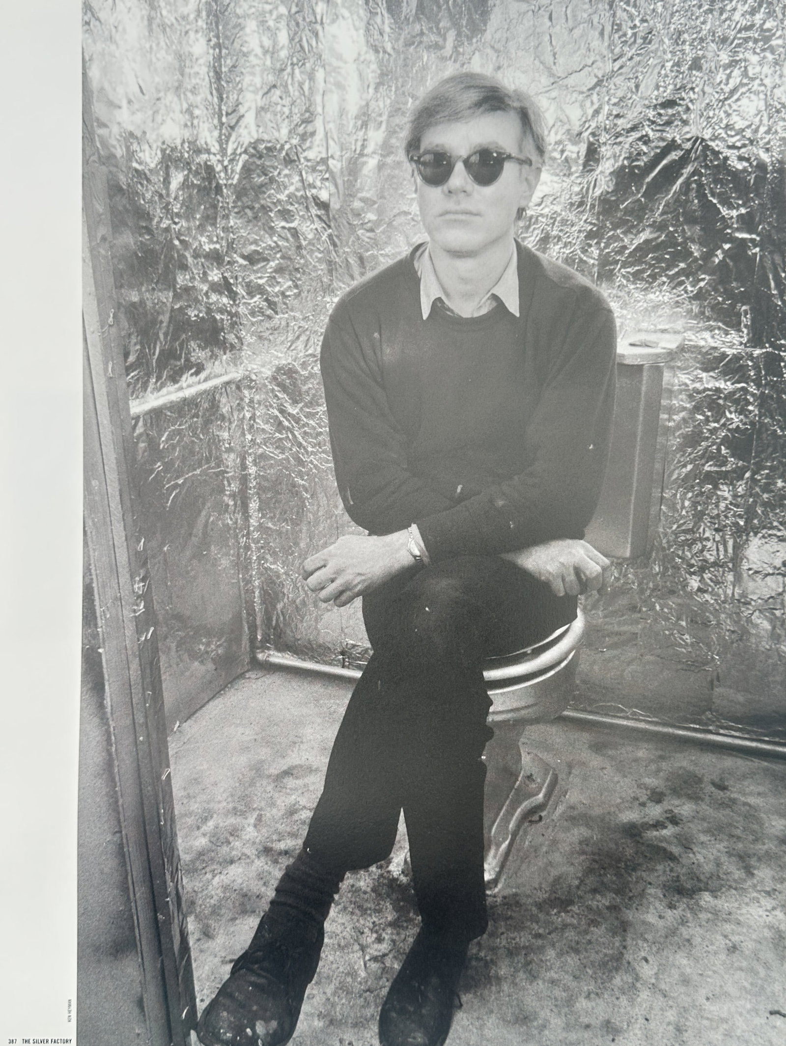 Andy Warhol, after – Portrait of the Artist – Offset lithographic reproduction (2006): "Untitled" The work presents a black and white photographic portrait of the artist wearing sunglasses while seated indoors against a crumpled metallic foil background. This print is derived from the p