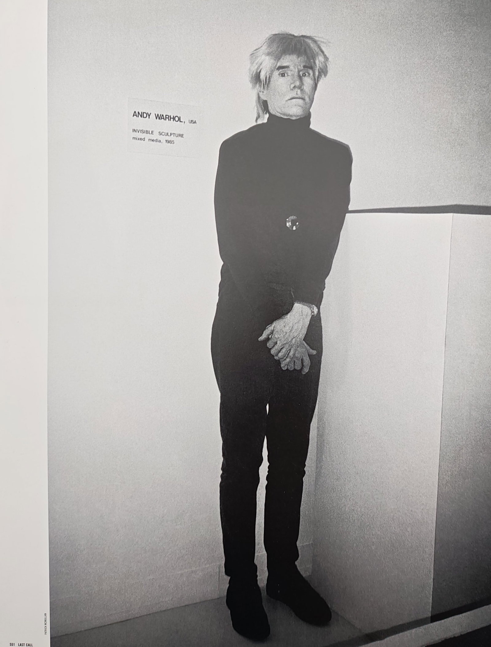 Andy Warhol,after – Invisible Sculpture – Offset print (20th Century): "Invisible Sculpture" illustrates the artist standing in dark attire beside an exhibition wall label in a minimalist gallery space. The photographic portrait captures performance art, institutional di