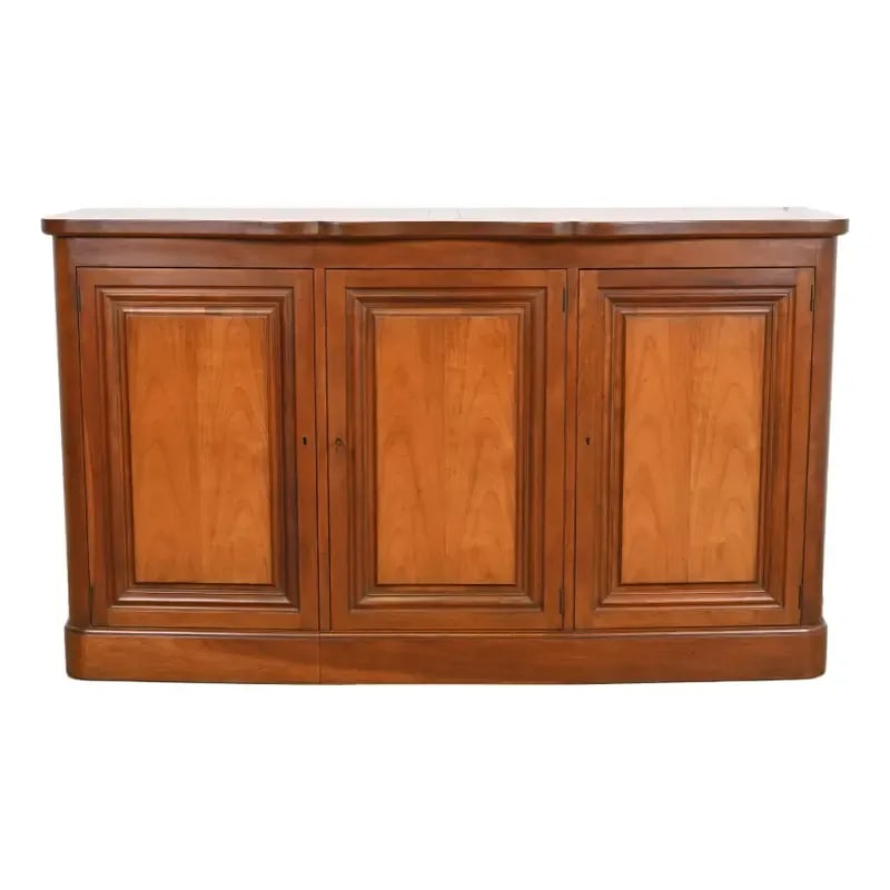 Baker Furniture Mid-Century French Regency Cherry Wood Sideboard or Bar Cabinet, Circa 1960s: An exceptional mid-century French Regency Louis XVI style sideboard, credenza, or bar cabinet By Baker Furniture USA, 1960s Gorgeous book-matched cherry wood. Cabinet locks, and key is included. Measu