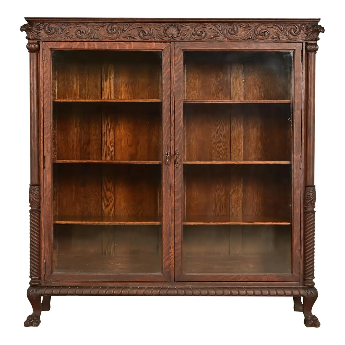 R. J. Horner Style Victorian Oak Double Bookcase With Carved Lion Heads and Paw Feet, Circa 1890s: An outstanding antique American Empire or Victorian double bookcase cabinet with lion heads and paw feet In the manner of R.J. Horner & Co. USA, Circa 1890s Carved quarter sawn oak, with glass front d
