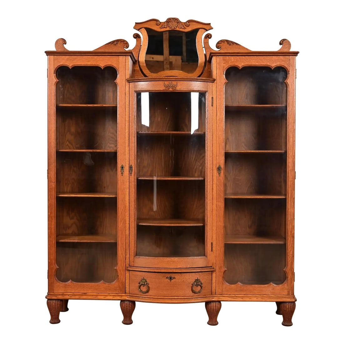 R. J. Horner Style Antique Victorian Carved Oak Triple Bookcase, Circa 1880s: An exceptional antique Victorian or Renaissance Revival triple bookcase, display cabinet, or bar cabinet In the manner of R.J. Horner & Co. USA, Circa 1880s Carved oak, with glass front doors, and ori
