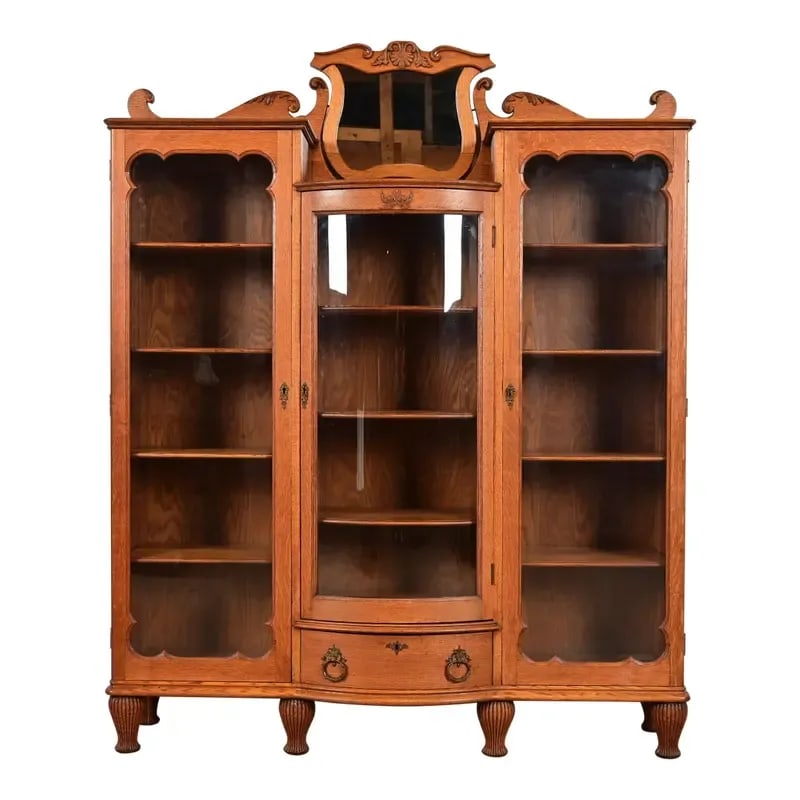 R. J. Horner Style Antique Victorian Carved Oak Triple Bookcase, Circa 1880s: An exceptional antique Victorian or Renaissance Revival triple bookcase, display cabinet, or bar cabinet In the manner of R.J. Horner & Co. USA, Circa 1880s Carved oak, with glass front doors, and ori