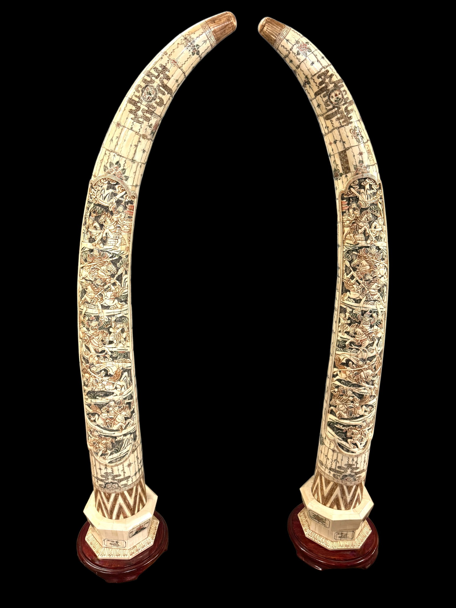 STUNNING Pair 6' Asian Carved Bone Tusk-Forms: A pair of massive paneled/tessellated carved bone in tusk-form depicting warriors. Crosshatch and colorations adorn these stunning hand carved works of art. Each are on a wooden stand adding to the gr