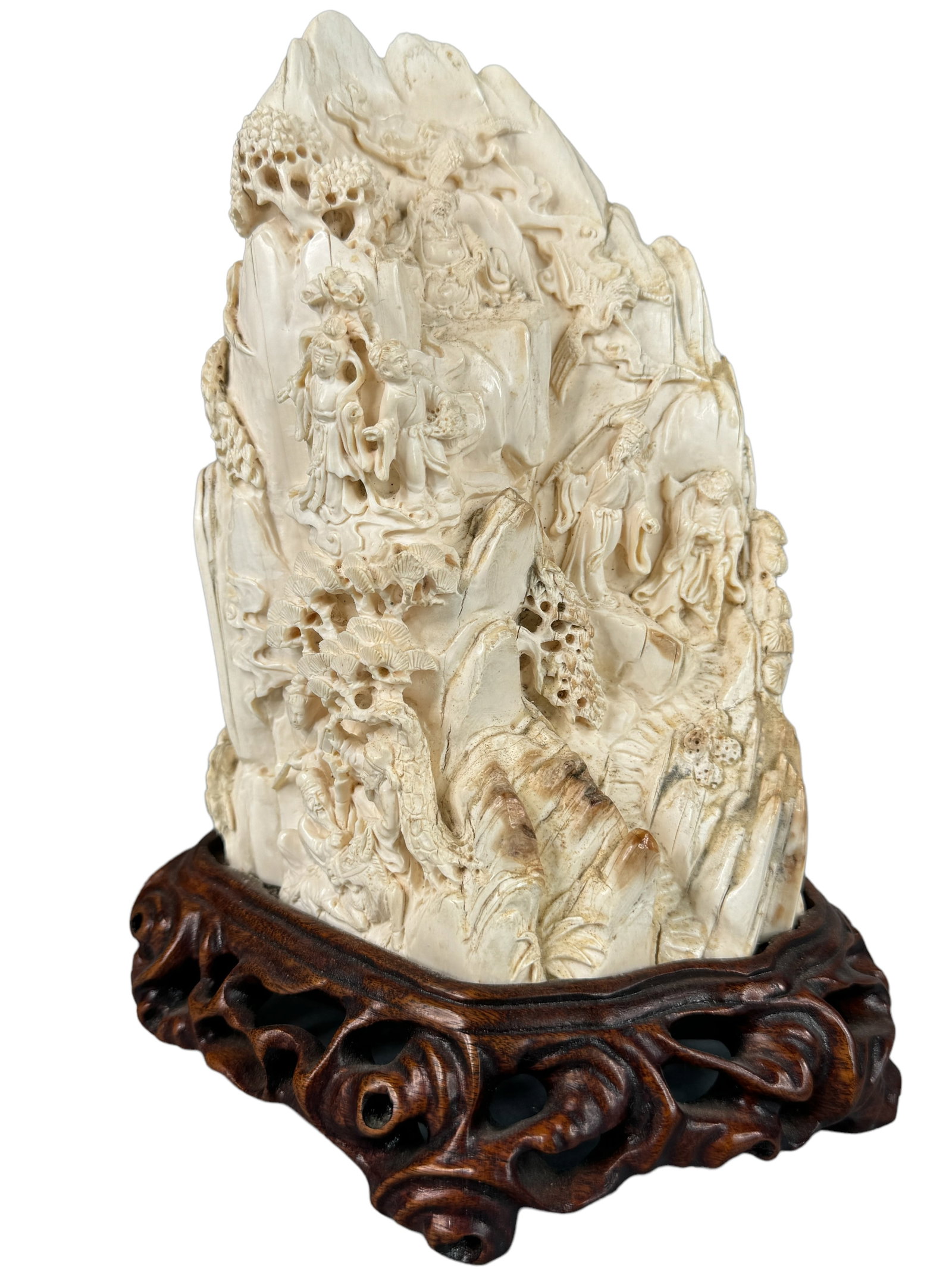 Detailed Mammoth Tusk Carving: Expertly carved mammoth tusk fragment depicting scenes of men playing checkers, men on a mountain ledge, monkeys, foliage and trees among clouds. Towards the top there is what appears as an immortal a
