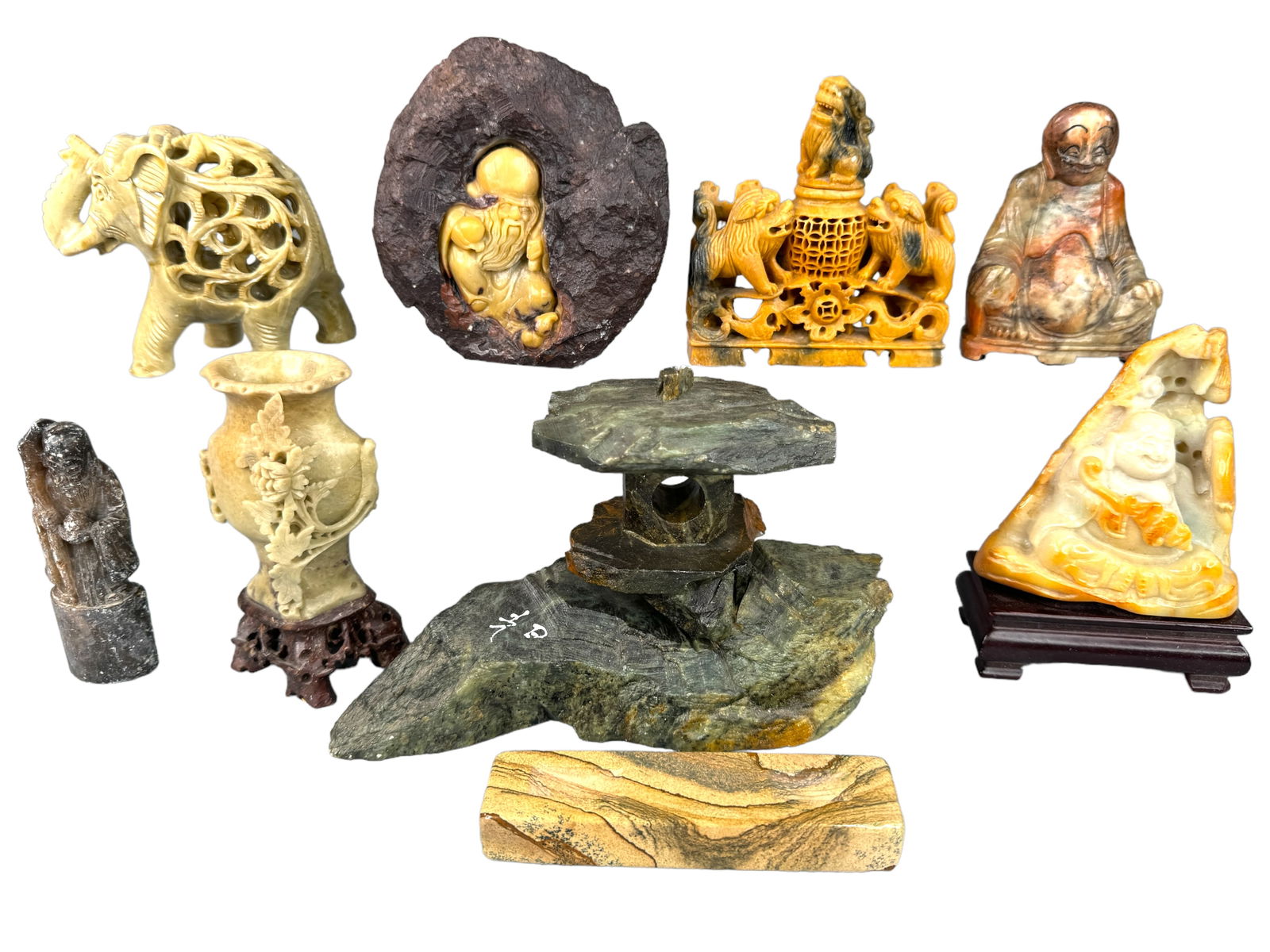 Carved Stone Asian Collection: Several carved stone Asian collectibles. Buddhas, small vase, a pagoda, a foo lion mini censer, and an elephant PLUS. Tallest item is 5 inches tall. One may be raw jade.