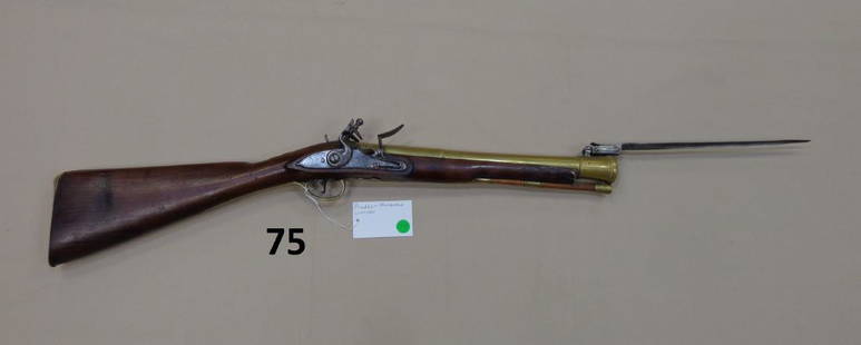 PRUDDEN BLUNDERBUSS, CIRCA 1800: FLINTLOCK WITH 14 1/2 IN. BRASS BARREL, FITTED WITH SPRING BAYONET ON TOP OF THE BARREL, BRASS TRIM THROUGHOUT THE RIFLE WITH ROSSETTES & SHELL ENGRAVINGS - FAIR, WALNUT STOCK HAS SEVERAL CRACKS & SPL