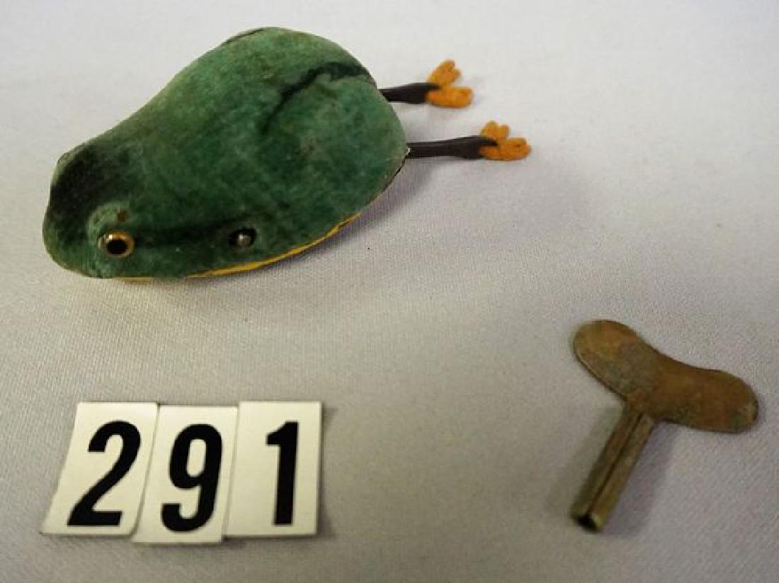 SCHUCO 4 INCH LONG KEY WIND-UP FROG: WITH GLASS EYES, PAINTED GREEN FELT BODY WITH BLACK STRIPE DETAIL, LONG METAL LEGS WITH ORIGINAL FELT FEET, WORKING ORDER - GOOD