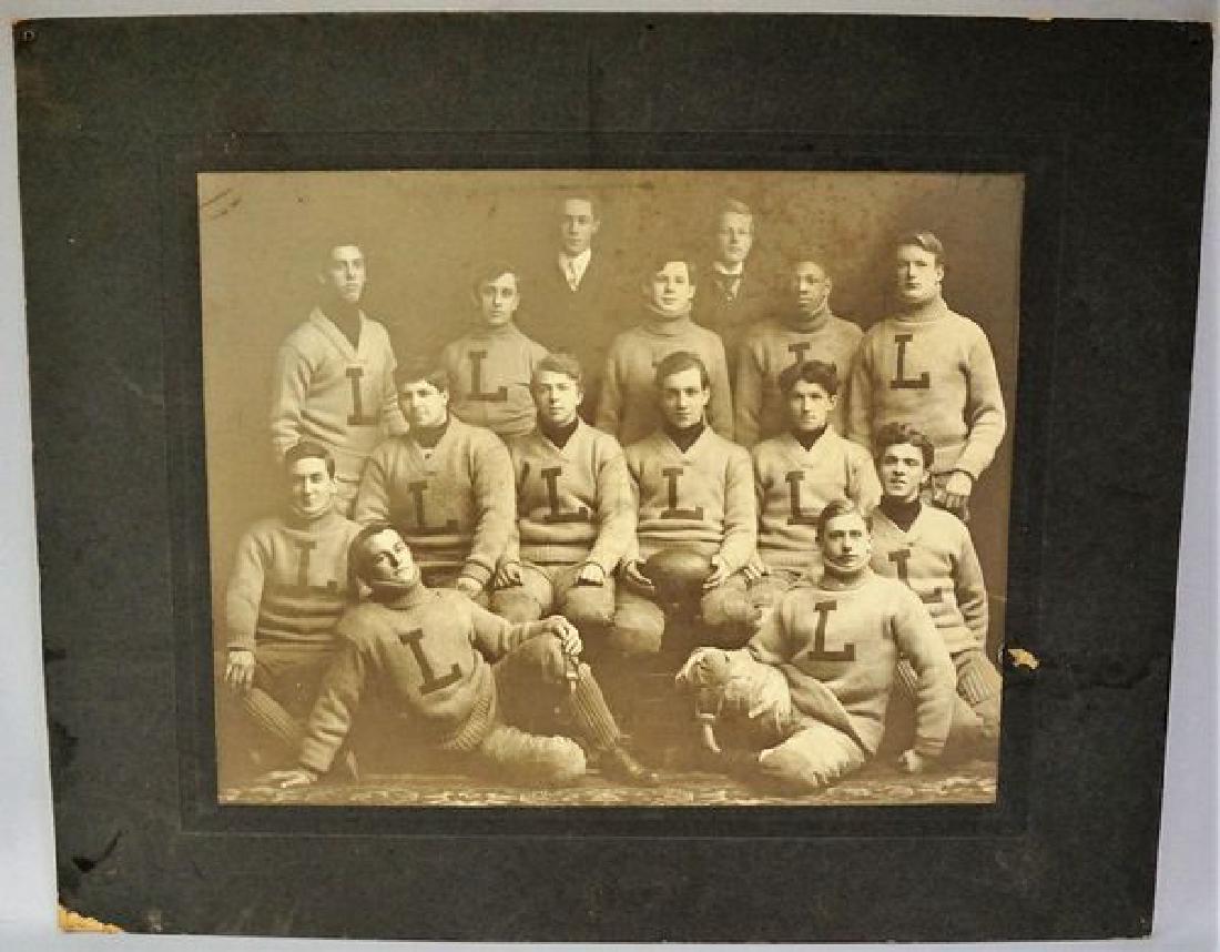 VINTAGE PHOTO OF 1904 FOOTBALL TEAM: (13) PLAYERS IN SWEATERS WITH LETTER 'L', EACH IN PADDED PANTS & SOCKS, PHOTO SIZE 11 IN. H, 13 3/4 IN. W, MAT SIZE 16 IN. H, 20 IN. W, IMAGE WITH SOME LIGHT SCRAPES & FOXING IN UPPER RIGHT, MAT WITH 