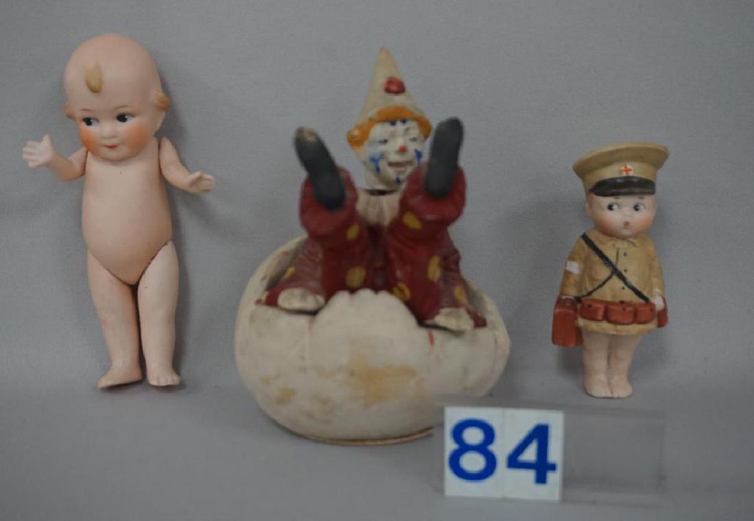 (3 PIECES) PAPIER MACHE EGG WITH BISQUE CLOWN NODDER: (3 PIECES) PAPIER MACHE EGG WITH BISQUE CLOWN NODDER SITTING ON THE TOP OF THE 'BROKEN' EGG (5 1/4 IN. H, 3 3/4 IN. W), SOME LOSS TO FINISH ON THE RIGHT SIDE OF THE EGG - FAIR TO GOOD, 4 IN. BISQUE IM