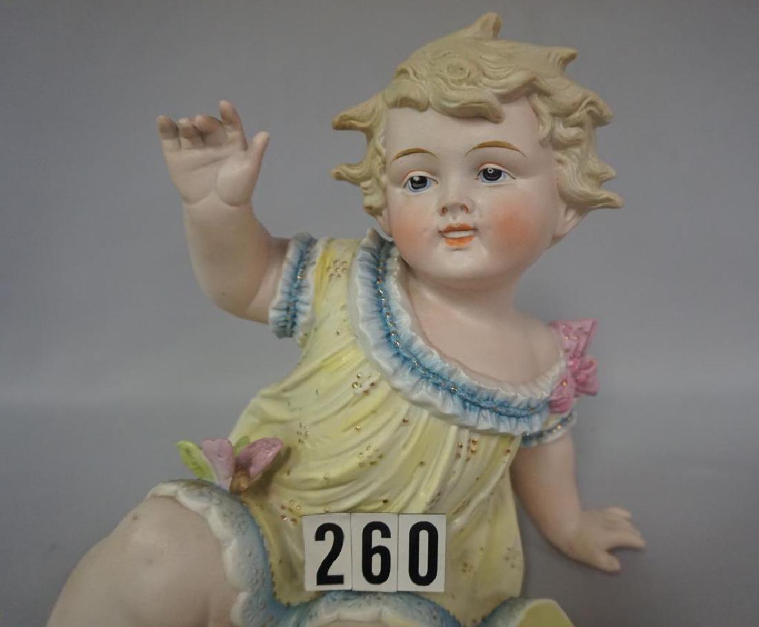 PAINTED BISQUE PIANO BABY (CONTRA & BOEHME), APPROX. 8: PAINTED BISQUE PIANO BABY (CONTRA & BOEHME), APPROX. 8 1/2 IN. H, BASE IS 6 1/2 IN. W AT WIDEST POINT, BABY IS IN SITTING POSITION WITH LEFT ARM SUPPORTING HER, RIGHT ARM IS IN RAISED POSITION, BUTTER