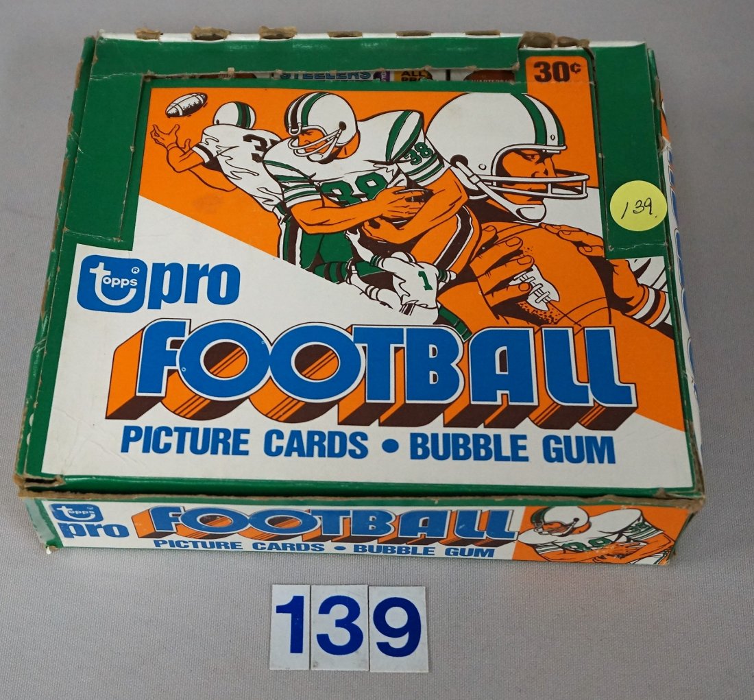 1979 TOPPS FOOTBALL CELLO BOX: WITH 24 UNOPENED CELLO PACKS - N.MT., ORIGINAL FACTORY BOX, FRONT & BACK CORNERS ON LEFT SIDE OF BOX ARE SPLIT & TAPED, BOX ALSO HAS WEAR IN OTHER AREAS - GOOD