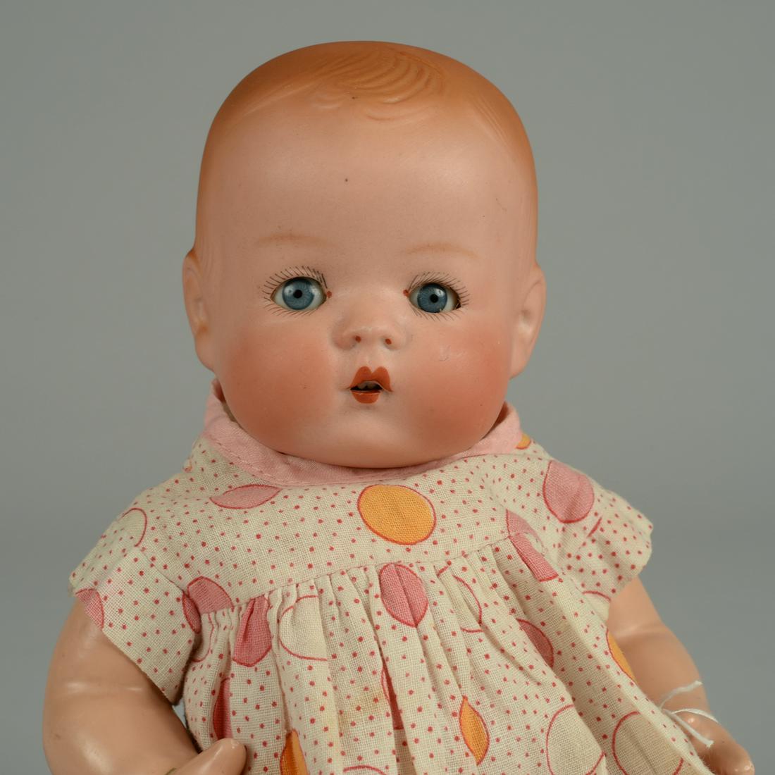 RARE BISQUE SKIPPY BABY DOLL 9 1/2 IN.: GERMAN BISQUE FLANGE HEAD WITH BLUE SLEEPING EYES, OPEN MOUTH WITH TWO UPPER TEETH, MOLDED HAIR, COMPOSITION FIVE PIECE EFFANBEE BODY, ORIGINAL PRINTED COTTON BABY DRESS