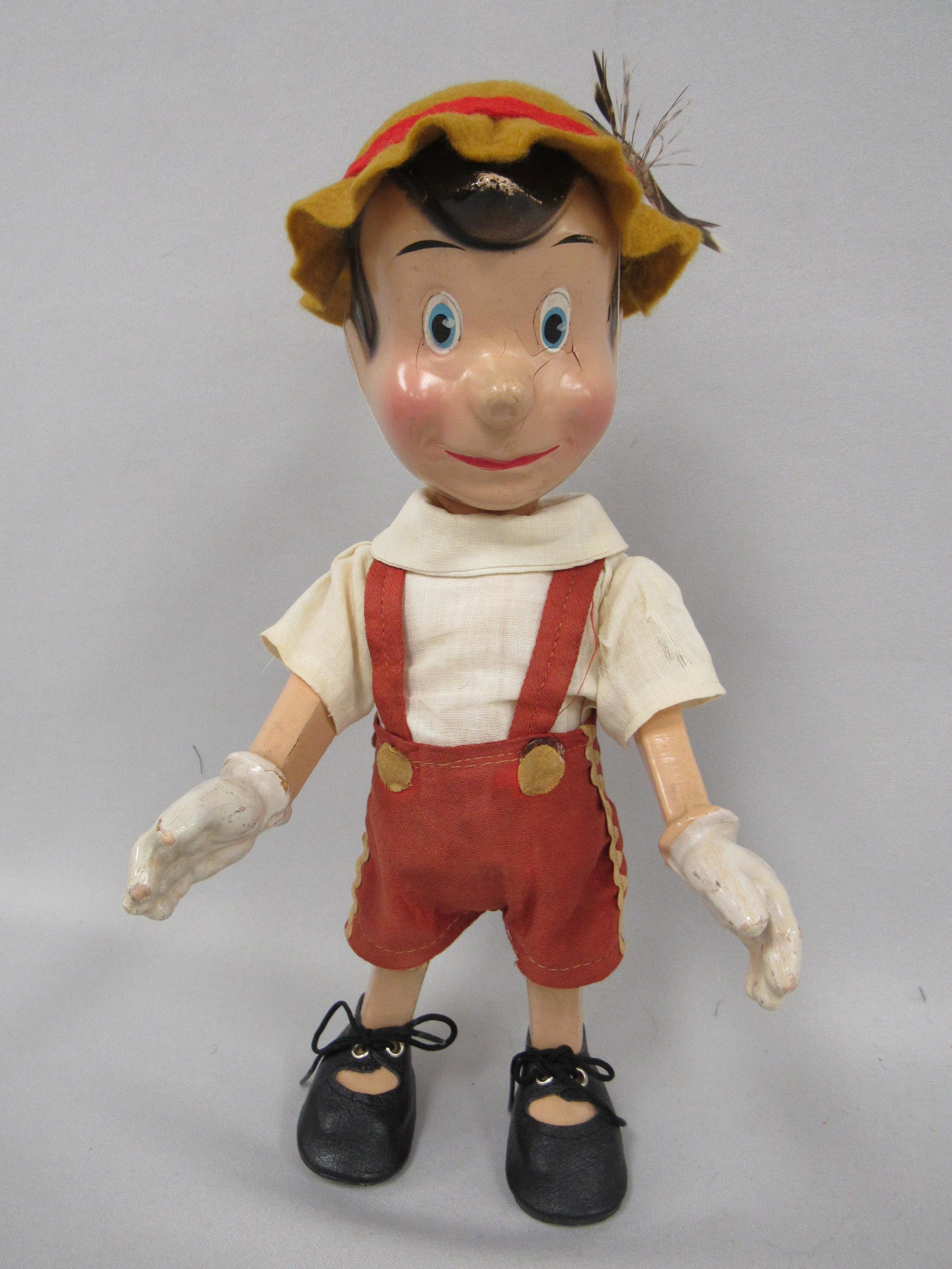 PINOCCHIO JOINTED COMPOSITION BODY:: MARKED W. DISNEY PROD. MADE IN USA. CROWN TOY CO. CIRCA 1939. VERY GOOD CONDITION. SOME CRAZING AROUND EYES & LEFT SIDE OF MOUTH. ORIGINAL CLOTHING WITH SOME SHREDDING TO LEFT SLEEVE. REPLACED HAT & S