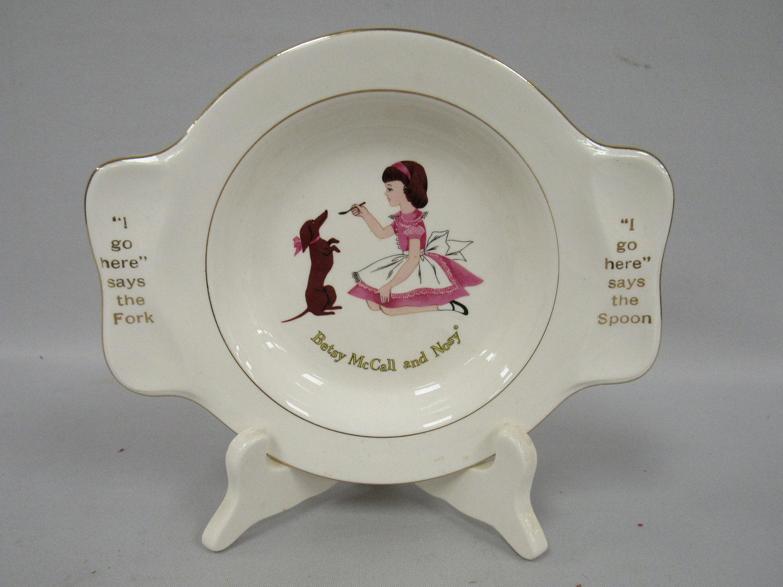 BETSY McCALL PLATE PICTURING BETSY FEEDING HER DOG: - NOSY. MADE BY HOMER LAUGHLIN CHINA CO., CLEAN 9 IN. W X 6 3/4 IN. H - VERY GOOD