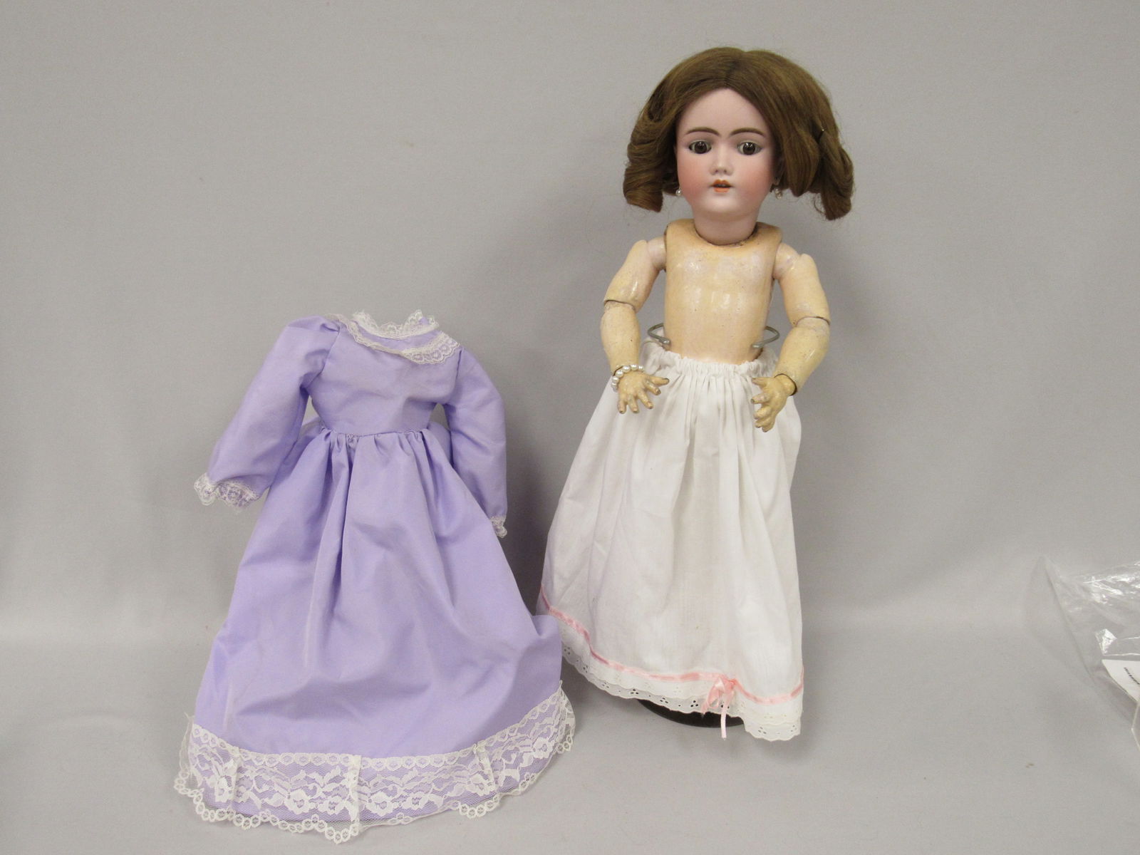 HANDWERK 23 IN. MARKED 99-11 3/4 DEP:: GERMANY HANDWERK 3 1/2. BISQUE HEAD- CHIPPED AT NECK OPENING WITH A HAIRLINE RUNNING TO LEFT EAR. REPLACED EYES, O.M. COMPO BODY HAS NORMAL WEAR. LOWER RIGHT ARM IS SPLIT ELBOW TO WRIST - FAIR/GOOD