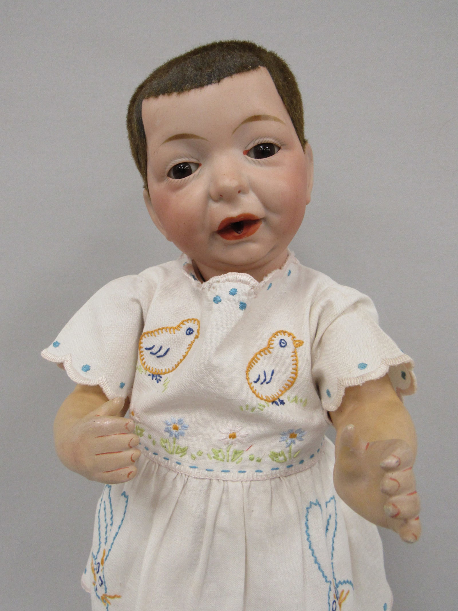 15 IN. FLOCKED HAIR NURSING BABY:: BALD BISQUE SOCKET HEAD INCISED 1, MOLDED & PAINTED FEATURES, STATIONARY BROWN GLASS EYES, UNIQUE MOUTH WITH SMALL HOLE FOR NURSING BOTTLE, ON HIS ORIGINAL FIVE-PIECE BABY BODY, WEARING HOMEMADE BABY