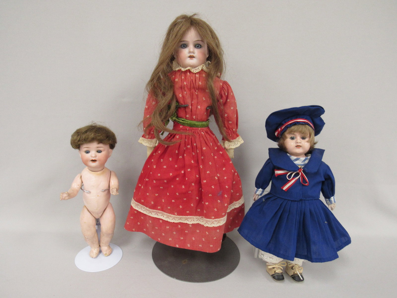 (3) ANTIQUE DOLLS:: INCLUDES 11 ½ IN. TIN HEAD, GLASS EYES, OPEN MOUTH WITH TEETH. KID BODY WITH CELLULOID LOWER ARMS & LEGS. 9 IN. HEUBACH-KOPPELSDORF MARKED 300-13/0 GERMANY. CLEAN HEAD & BODY (CRACK REPAIR ON B