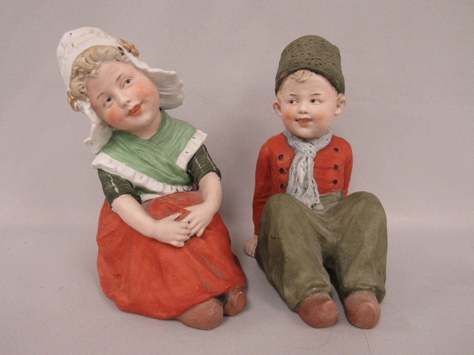 7 IN. HEUBACH DUTCH BOY & GIRL PIANO BABIES:: ALL BISQUE DUTCH BOY & GIRL FIGURES, WELL MODELED & PAINTED, BOTH INCISED WITH HEUBACH TRADEMARK SUNBURST ON BOTTOM. PERFECT BISQUE ON BOTH