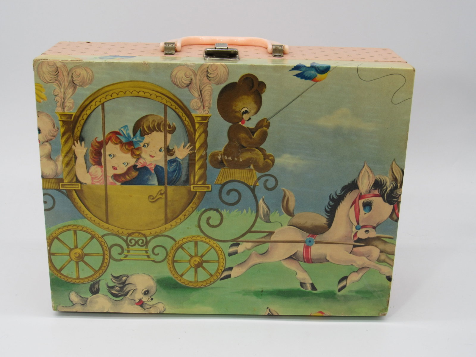 DOLL TRUNK/SUITCASE:: COLORFUL GRAPHICS FROM 40'S - 50'S 9 IN. H X 12 IN. W X 3 3/4 IN. D, CHILDREN IN A CARRIAGE PULLED BY DONKEYS. CONTAINS ASSORTED GINNY OUTFITS (9-7 TAGGED), SOME PAPER LIFTING AT CORNERS & SEAMS