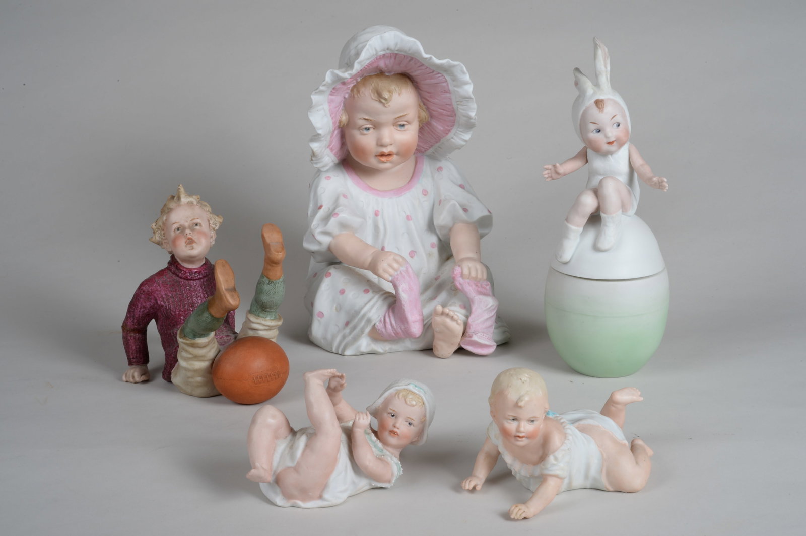 (5) GEBRUDER HEUBACH FIGURES:: 3 1/4 IN. H TO 10 IN. H. GIRL WITH LARGE BONNET HAS A PAINT TOUCH-UP AT TOP OF BOOTIE ON HER RIGHT FOOT, ALSO A (WHITE) PAINT TOUCH-UP ON SLEEVE OF HER LEFT ARM, RABBIT EARS ON BOY WERE EACH MENDED & 