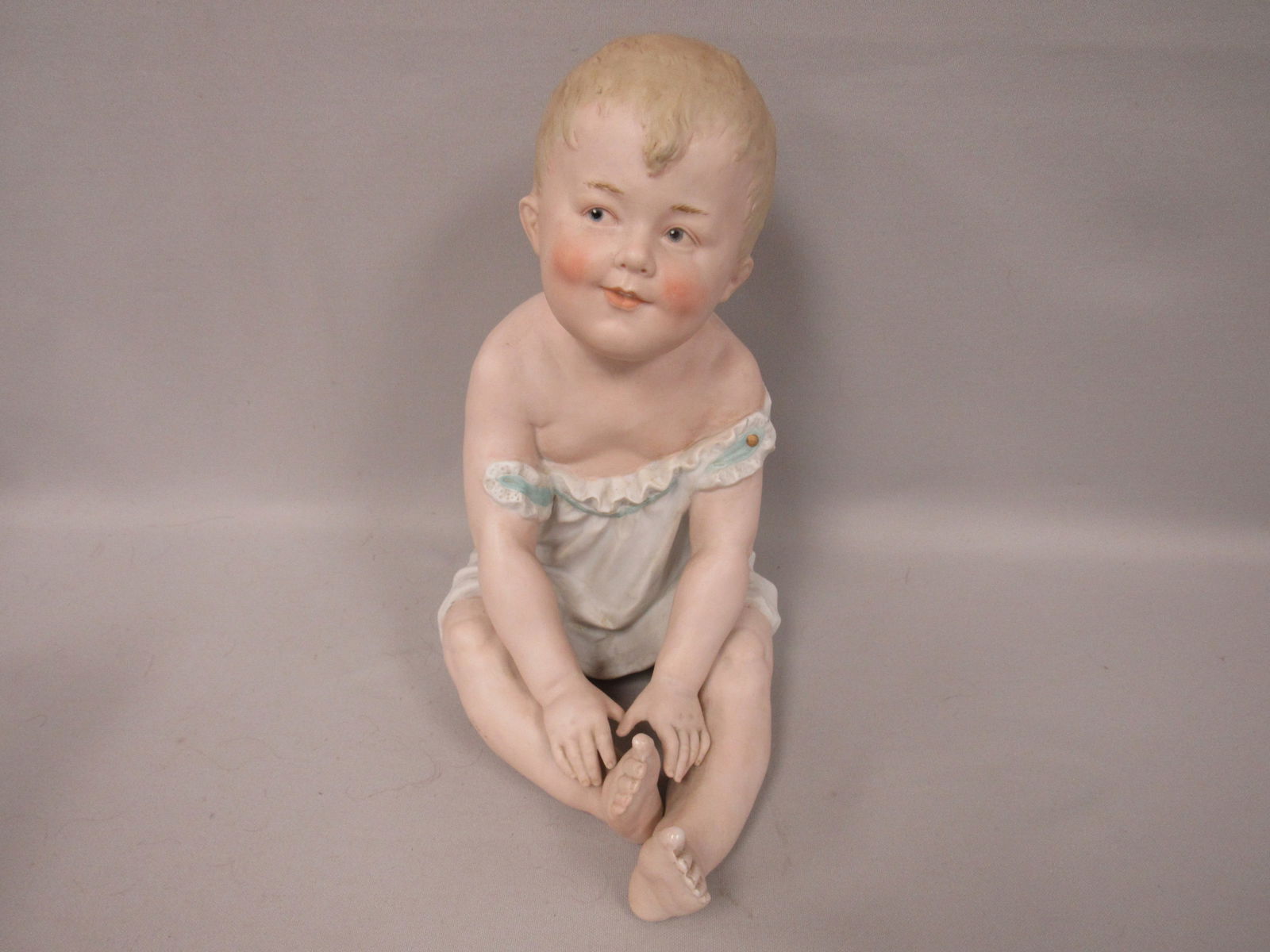 LARGE BISQUE HEUBACH PIANO BABY BOY:: 10 1/2 IN. H, 9 1/2 IN. L, 6 IN. W, "SUNBURST" MARK ON REAR SIDE OF OUTFIT, HAS SOME LIGHT SOILING & SCUFFS. NO DAMAGE OR REPAIRS