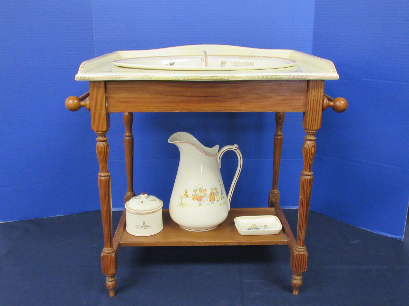 CHILD'S/DOLL'S ANTIQUE WASHSTAND:: THE PROCELAIN TOP OF STAND IS SIGNED "LAVABO-BEBE" SARREQUE MINIAS & DIGC IN (SEE PHOTO) THE ANTIQUE CHESTNUT WOOD STAND WITH SCENIC DECOR. ALSO INCLUDES 4 PCS. OF PORCELAIN SARRAEQUE MINIAS
