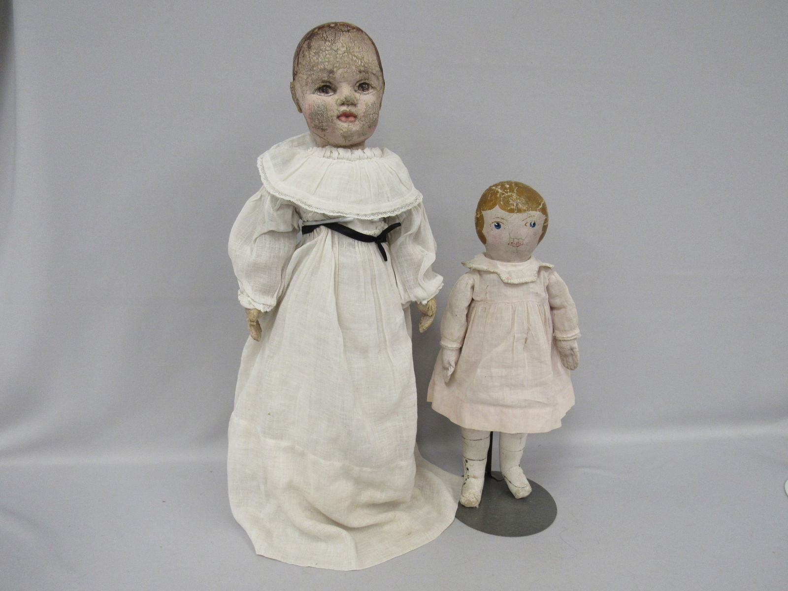 PAIR OF EARLY OIL PAINTED DOLLS:: 17 IN. PAINTED HEAD, HANDS & LOWER LEGS WITH PAINTED HIGH BOTTOM BOOTS. FACE HAS PAINT CRACKING. 21 IN. PAINTED HEAD & LIMBS, BODY IS STURDY WITH WEAR ON HANDS, FACE HAS MUCH WEAR, BUT FEATURES