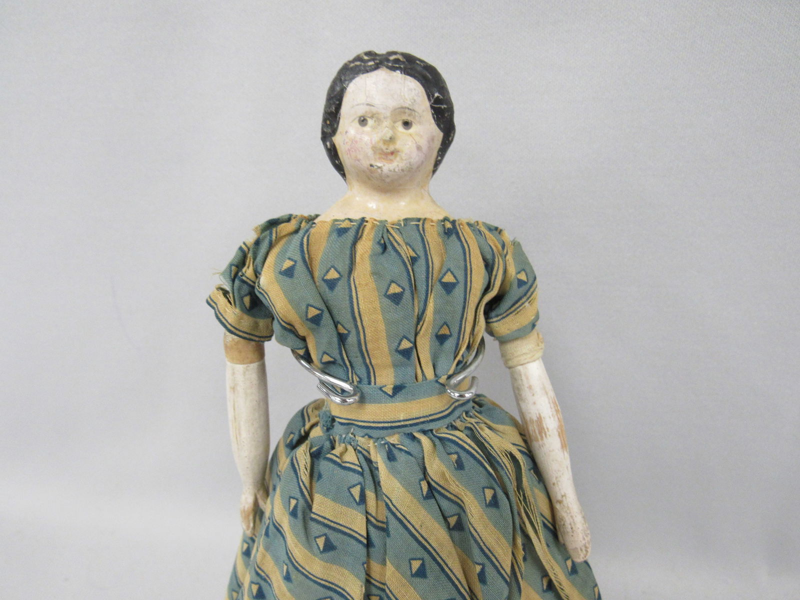 ANTIQUE 9 IN. MILLINERS MODEL:: DRESSED IN ORIGINAL DRESS & UNDERGARMENTS. HAS SOME TOUCH-UPS ON CHEEKS & FOREHEAD AREAS, OLD TAPE REPAIRS AT UPPER WOODEN ARMS & CLOTH ARM PORTION FROM BODY