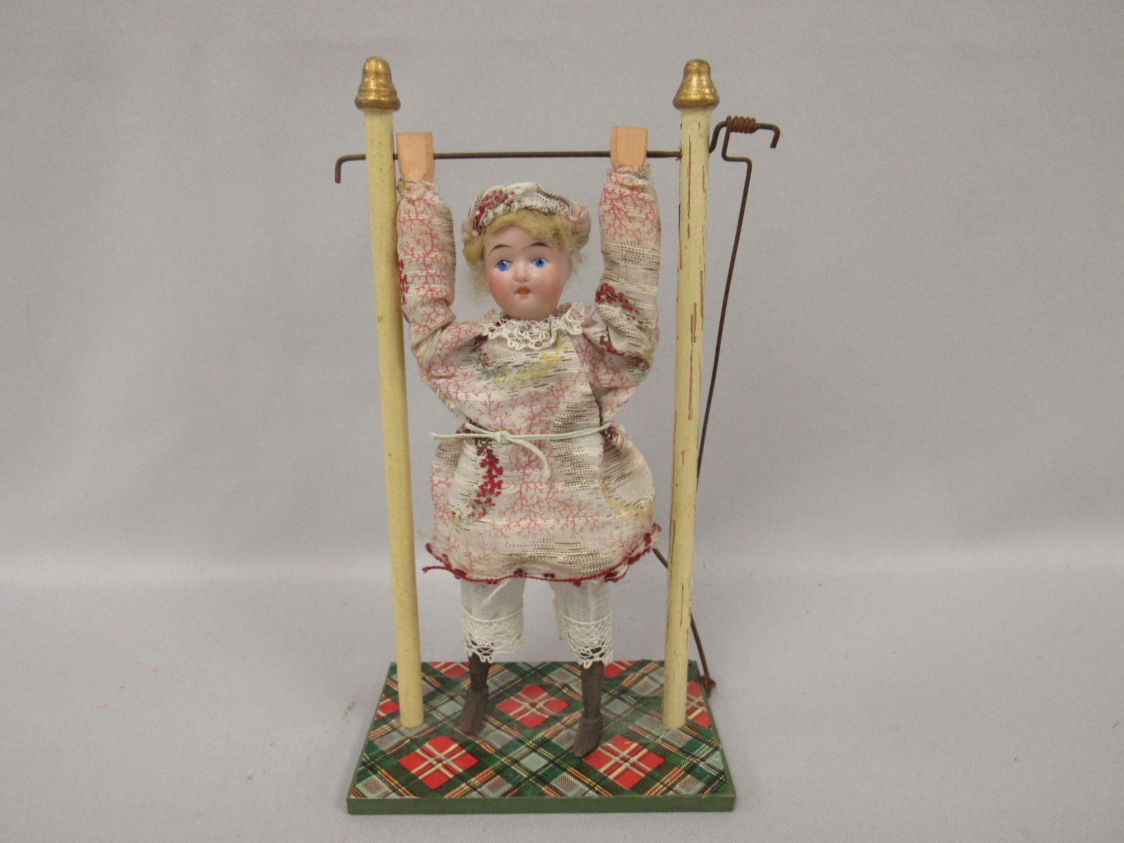GOEBEL 7 IN. ACROBAT GIRL WITH ORIGINAL STAND:: BISQUE FACE WITH PAINTED EYES, WOODEN TORSO, ARMS & LEGS. OUTFIT IS ORIGINAL AS WELL AS THE LEVER & SPRING WHICH MAKES HER DO COMPLETE SOMERSAULTS. NICE ADDITION TO ADD TO YOUR CABINET SIZE DOLLS