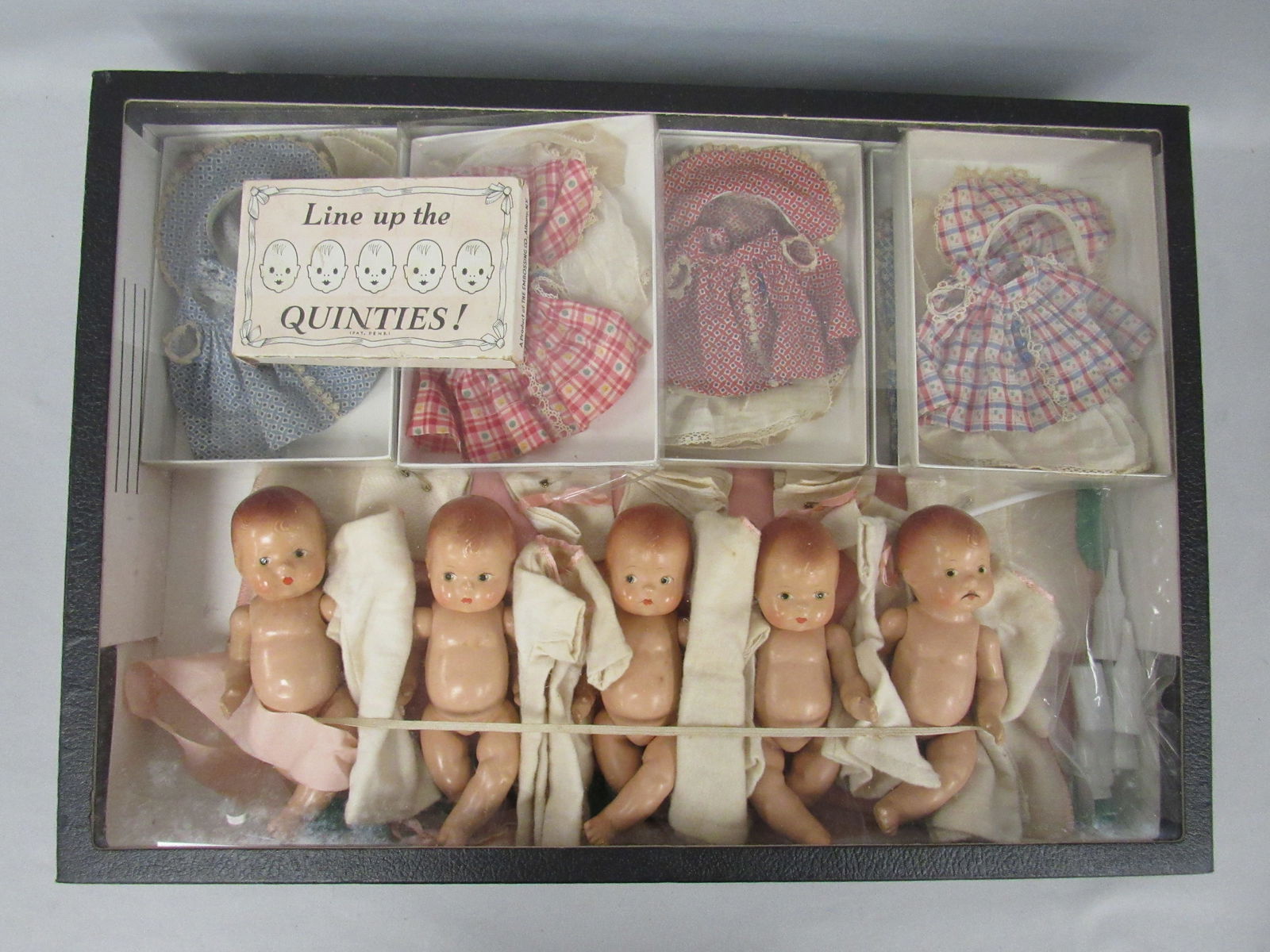 7 IN. EFFANBEE "BABY TINYETTE" QUINTS:: INCLUDES 5 DRESS & BONNET SETS, BOTTLES, DIAPERS, NIGHTGOWNS & A BOXED GAME - LINE UP THE QUINTS. DOLLS ARE ALL COMPOSITION, 2 HAVE CRACKS ACROSS THE MOUTH, ONE HAS A FLAKE OF PAINT ON LOWER LIP - G