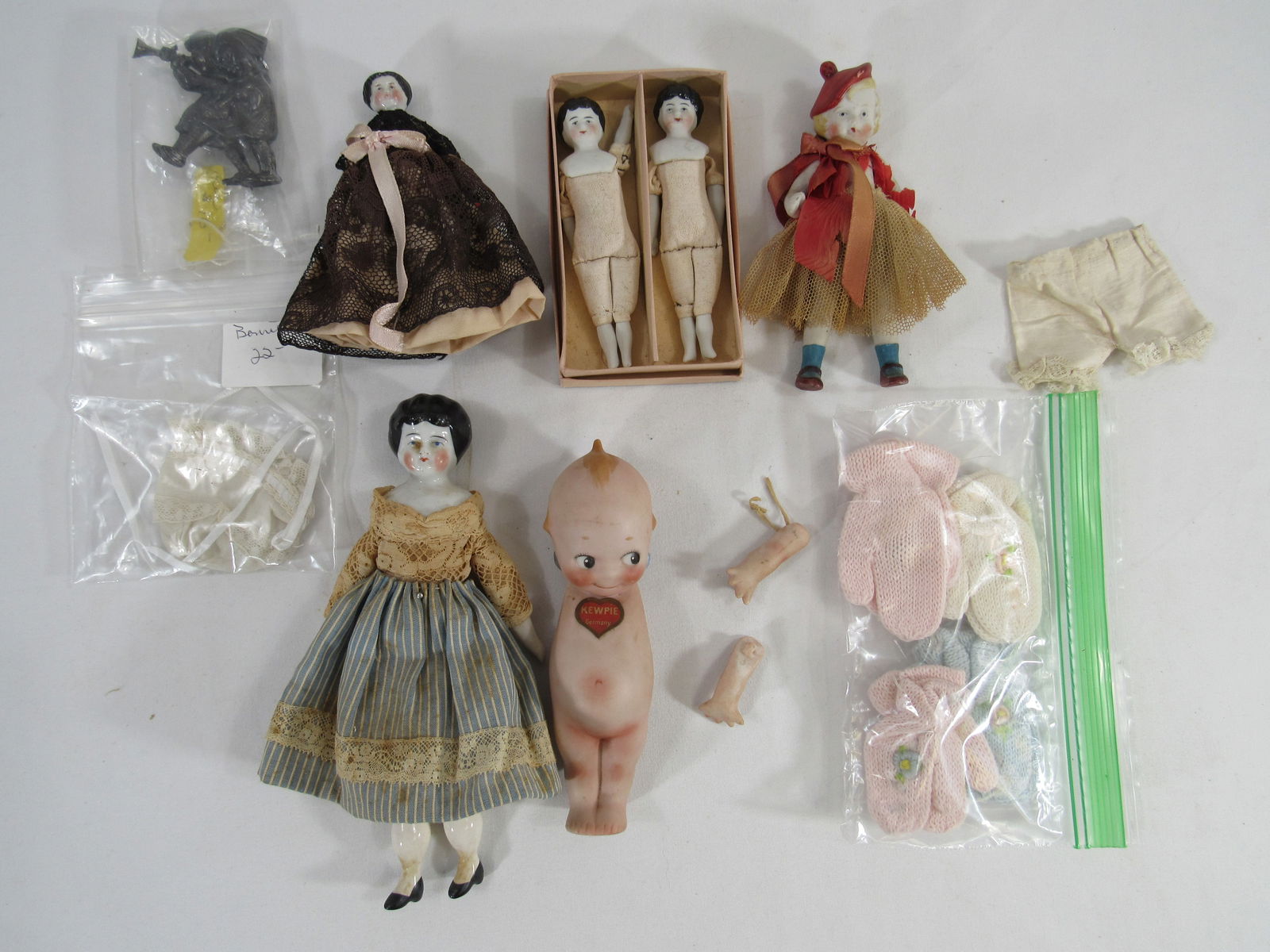 BOX OF CHINA & BISQUE DOLLS:: INCLUDES (2) 4 IN. CHINA LIMB DOLLS WITH BOX. 7 IN. CHINA HEAD & LIMBS (NEEDS CLEANING), 5 IN. CHINA HEAD & LIMBS, HEAVY PIN OF CHILDREN WITH TRUMPET & DRUM, 5 IN. 1930'S ALL BISQUE GIRL, 5.5 IN. KEWP
