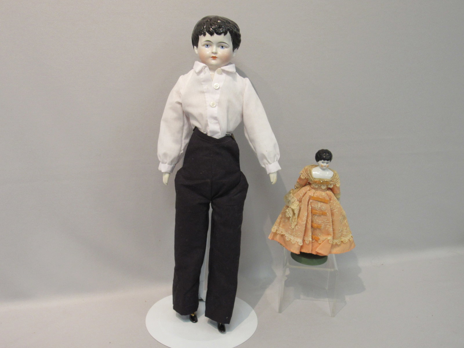 PAIR OF CHINA HEAD DOLLS:: 7.5 IN. LOW BROW GIRL CHINA SHOULDERPLATE, CHIP AT LOWER FRONT LEFT OF PLATE, STURDY CLOTH BODY WITH SOME STAINING AT LOWER LIMBS, HAS NOT BEEN UNDRESSED AS CLOTHING IS SEWN ON. 21 IN. CHINA HEAD BOY,