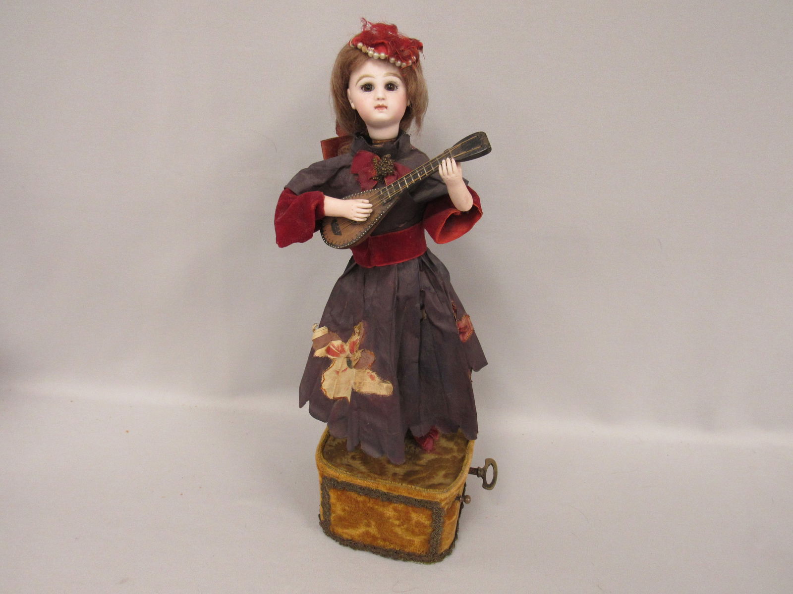 18 IN. FRENCH AUTOMATON GIRL:: ON A MUSIC BOX PLAYING A LUTE, BISQUE HEAD IS MARKED TETE JUMEAU (NO DAMAGE) SET EYES PIERCED EARS, BISQUE ARMS, CLOTHING IS FRAGINE, HAS KEY & WORKS - G