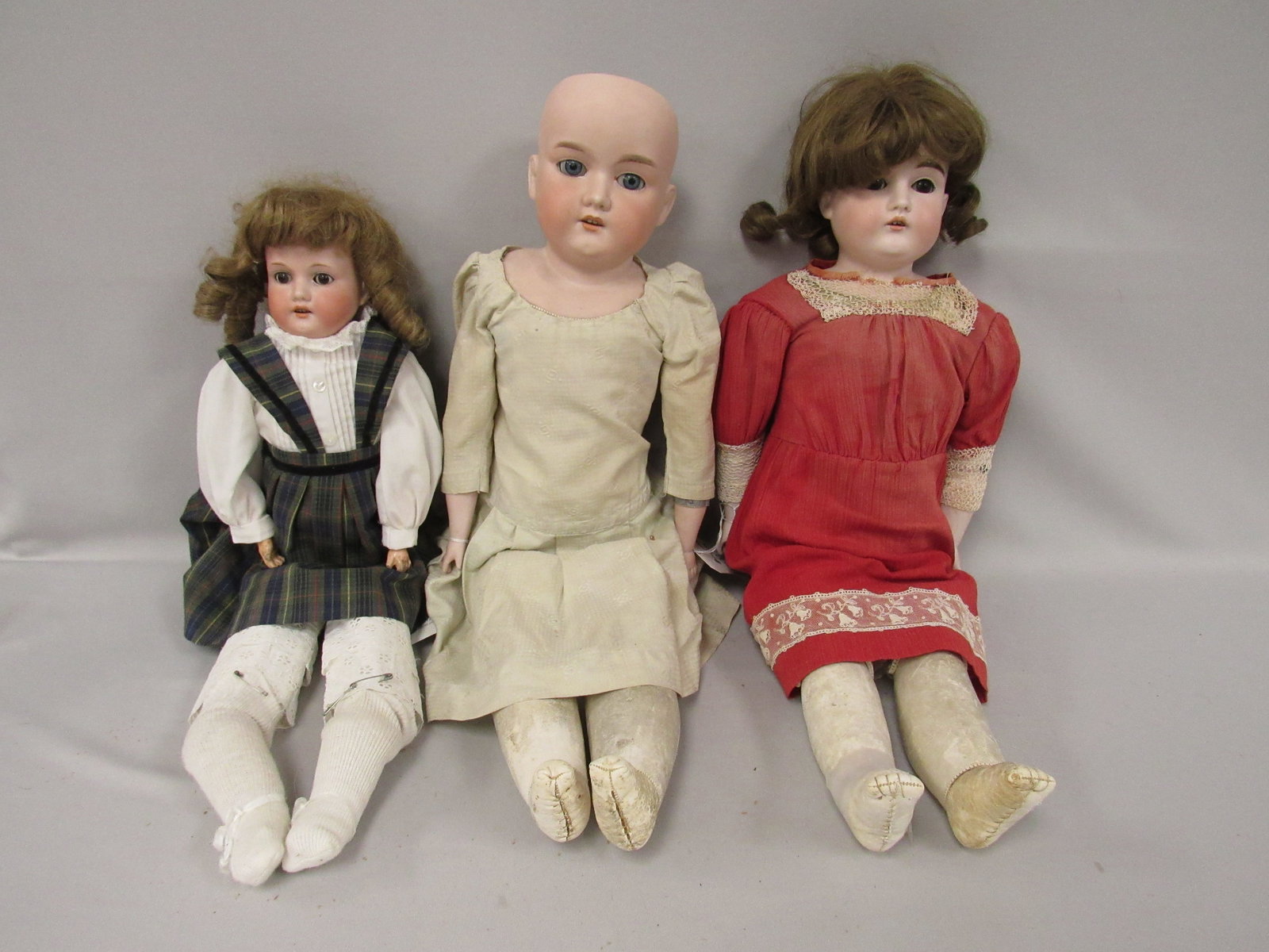 3 PCS.:: 26 IN. AM 370 SHOULDER HEAD WITH FIRING CRACKS IN HEAD OPENING, HAIRLINE ON BACK OF HEAD, GLASS EYES HAVE BEEN SET, SOME TEARS TO LEATHER BODY LOWER BISQUE ARMS, , VINTAGE CLOTHES. 22 IN. AM 370 WITH